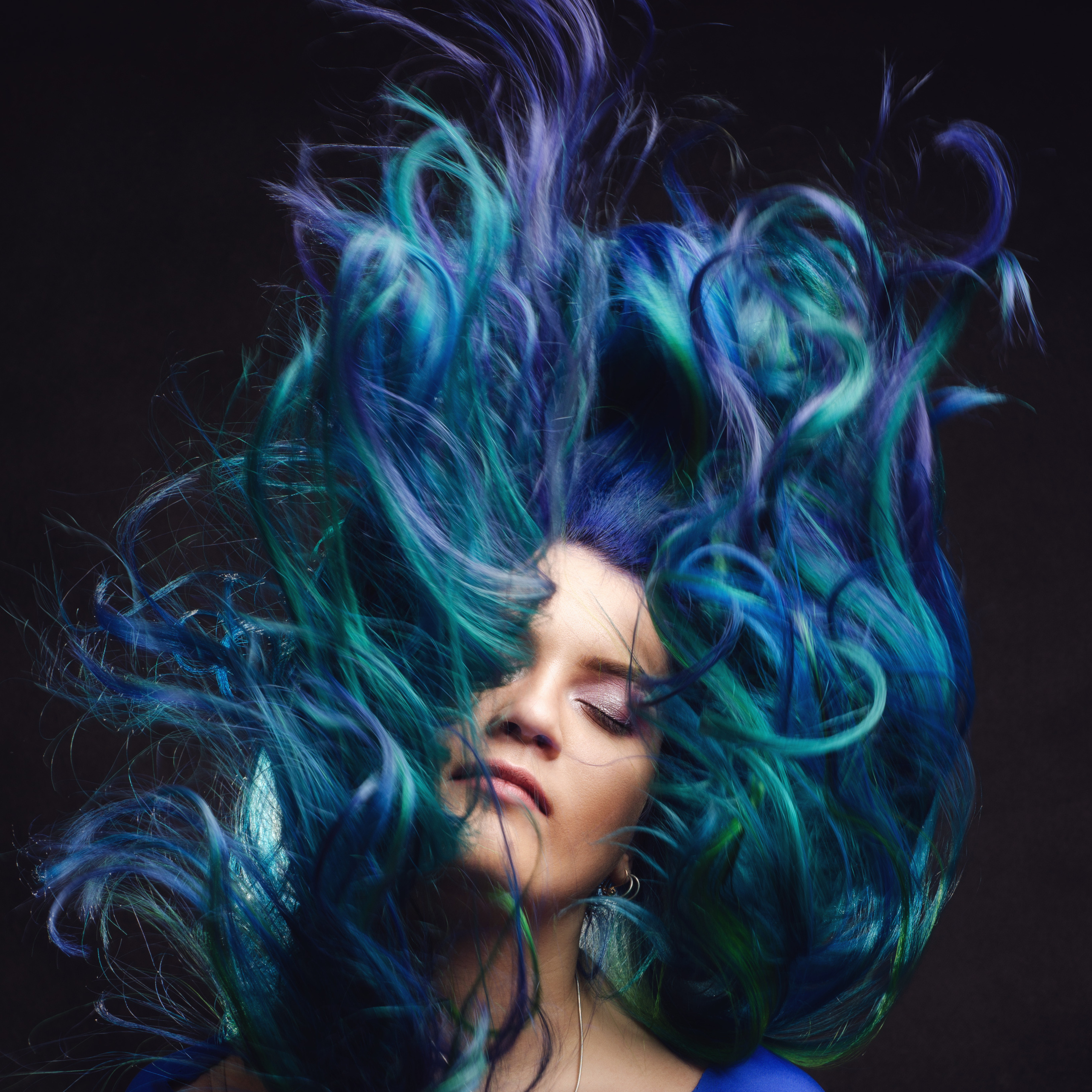 Студийный портрет девушки с закрытыми глазами и с фиолетовыми волосами, волосы волнами эффектно разлетаются в кадре 