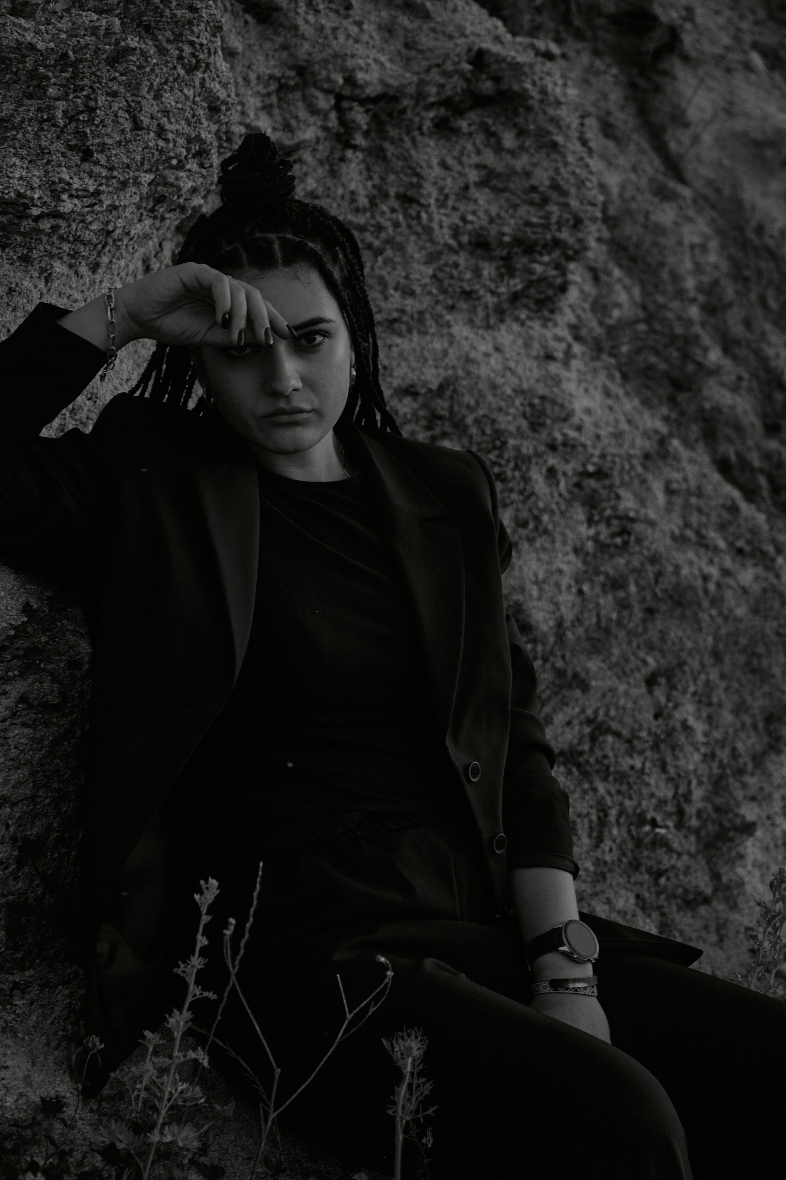 Молода жінка з афрокосами у чорному костюмі сидить на дерев'яному стільці у воді на тлі заходу сонця та зеленої природи