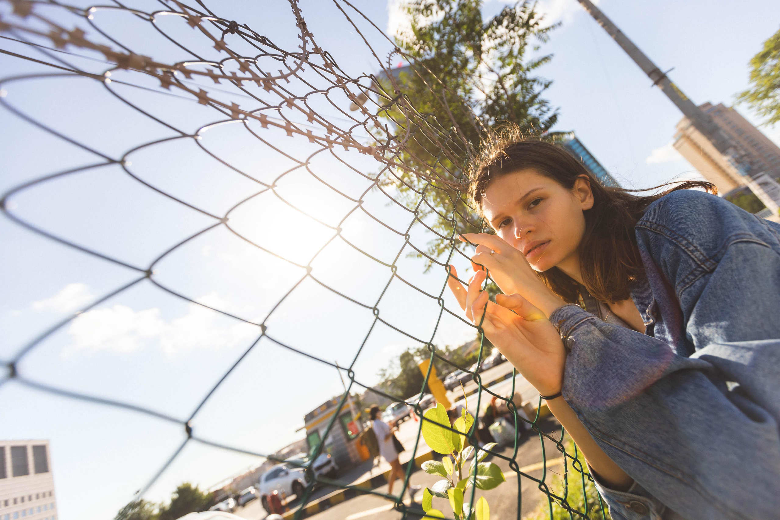 Девушка позирует возле плетенного забора