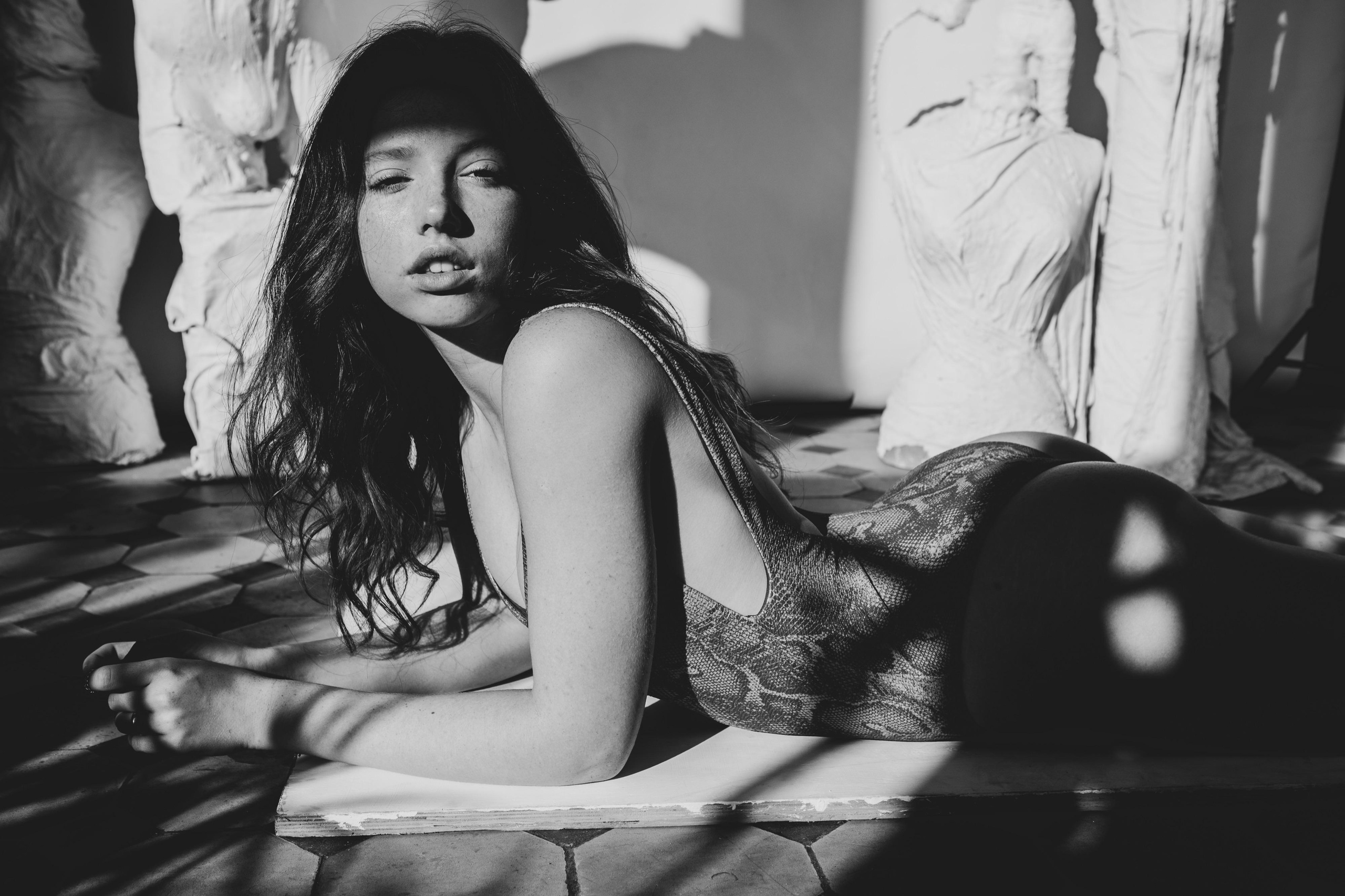 Модель в купальнике позирует фотографу лежа