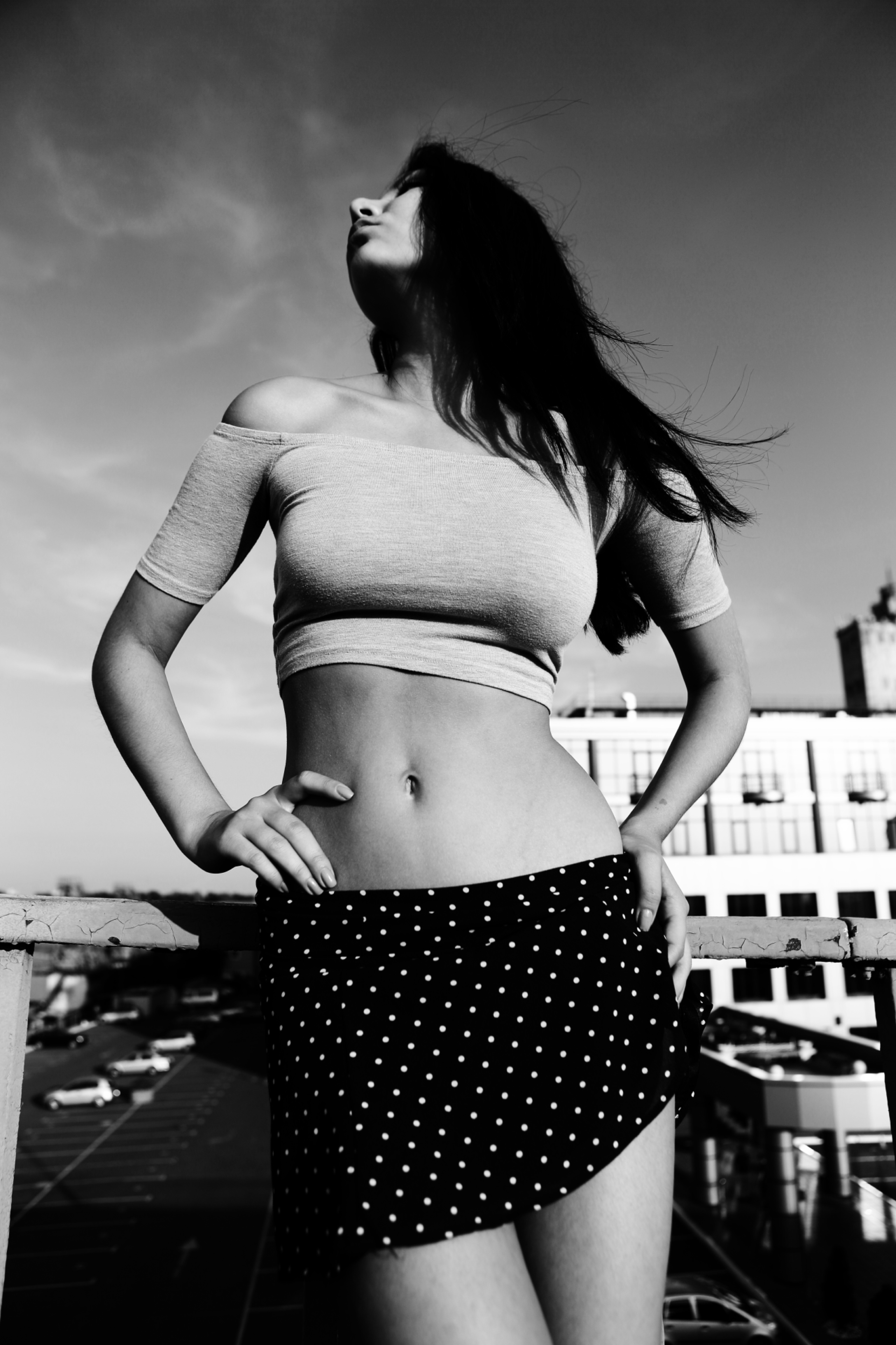 Портрет стройной девушки в топике и юбке в горошек на фоне промзоны