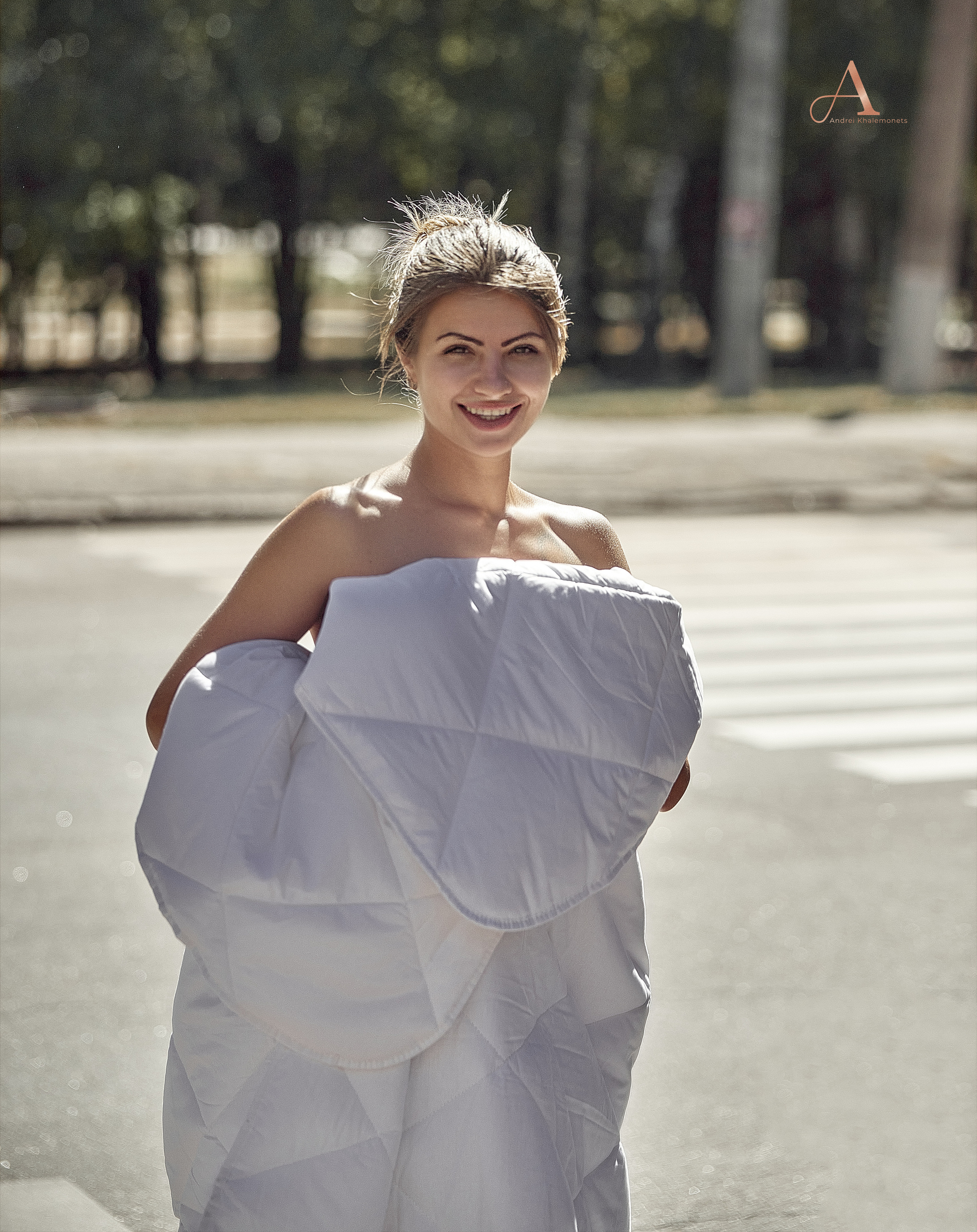 Девушка на дороге в центре города в одеяле.