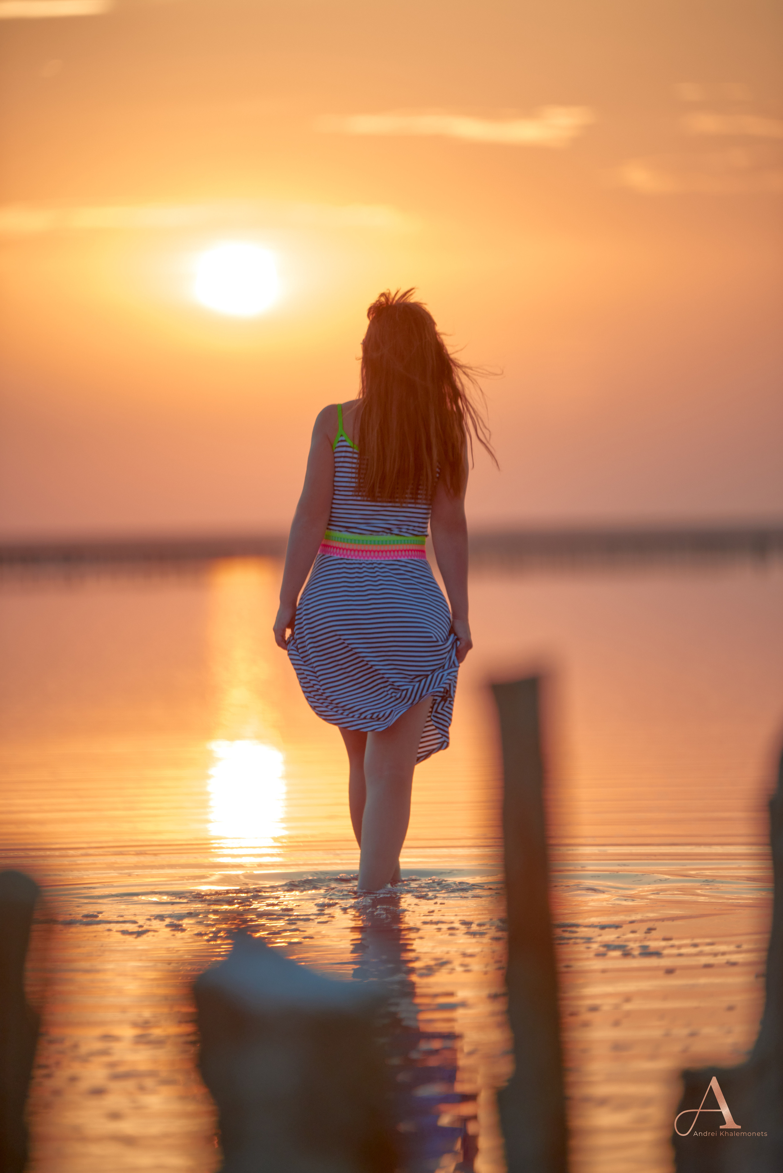 Фотосессия на Закате Розового Озера, девушка в платье идет по воде на встречу солнцу.