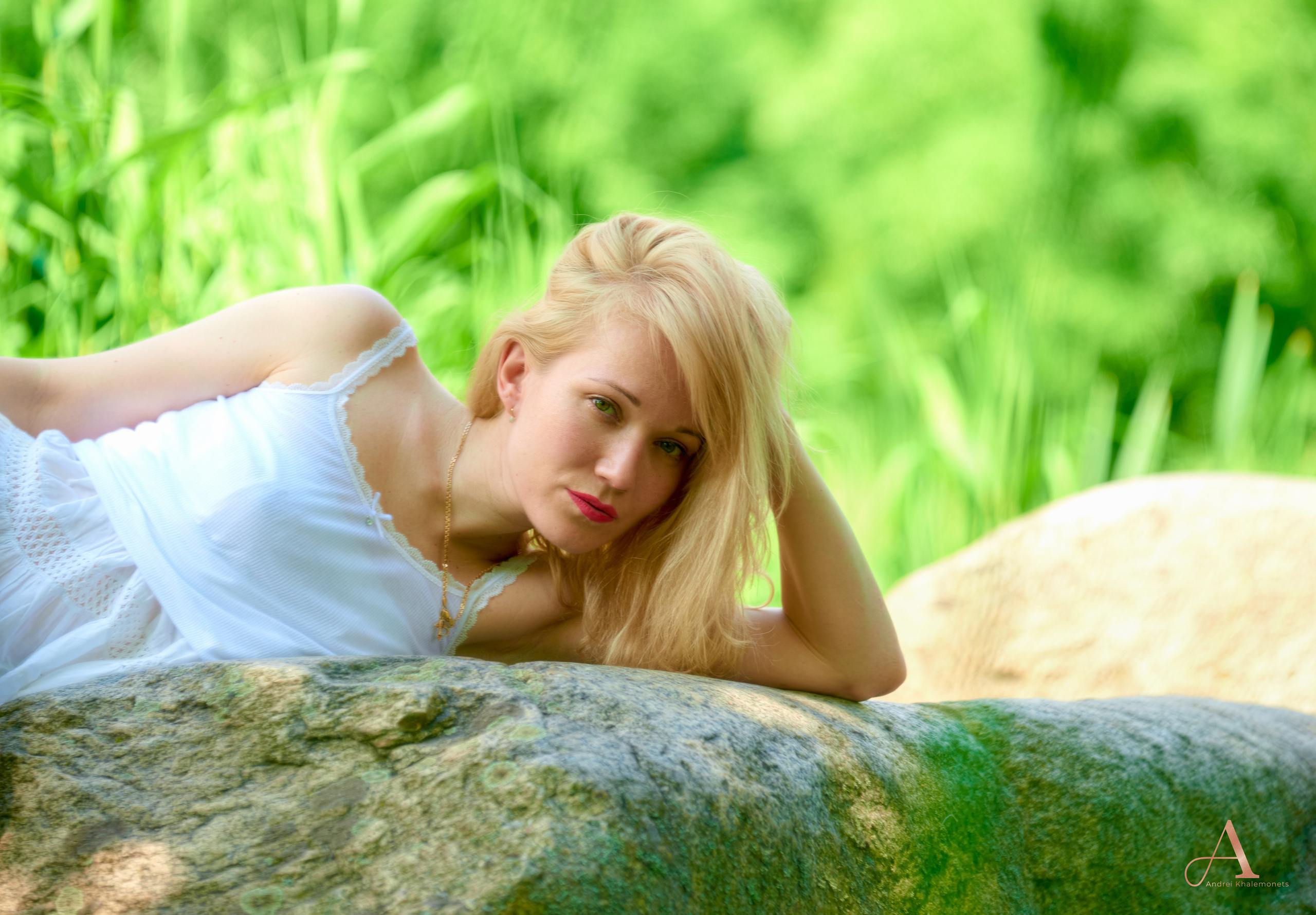 Девушка блондинка в белом лежит на камне, фотосессия на природе.