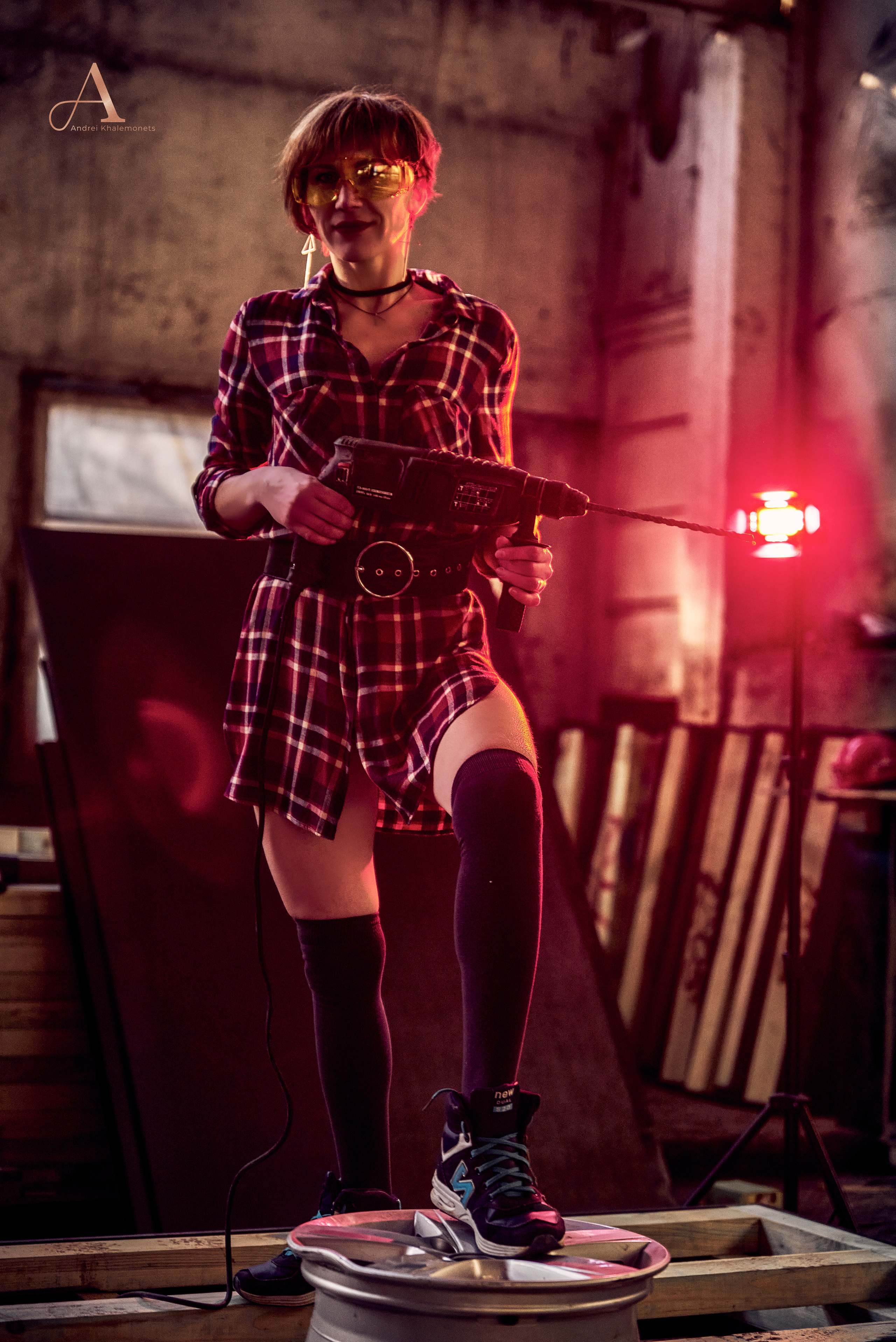 Девушка в черных гольфах с перфоратором.