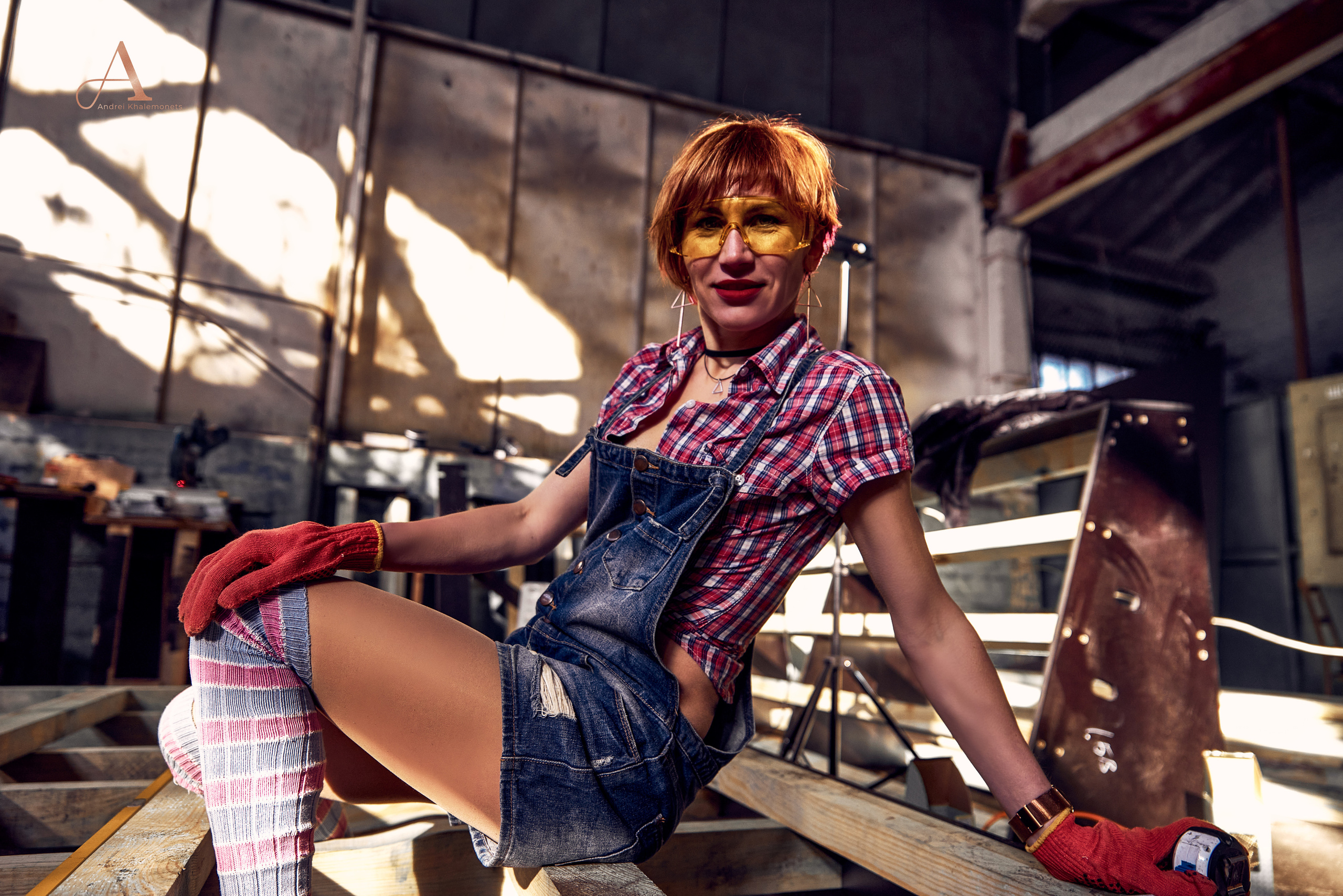 Девушка сидит на досках в слесарном цеху.