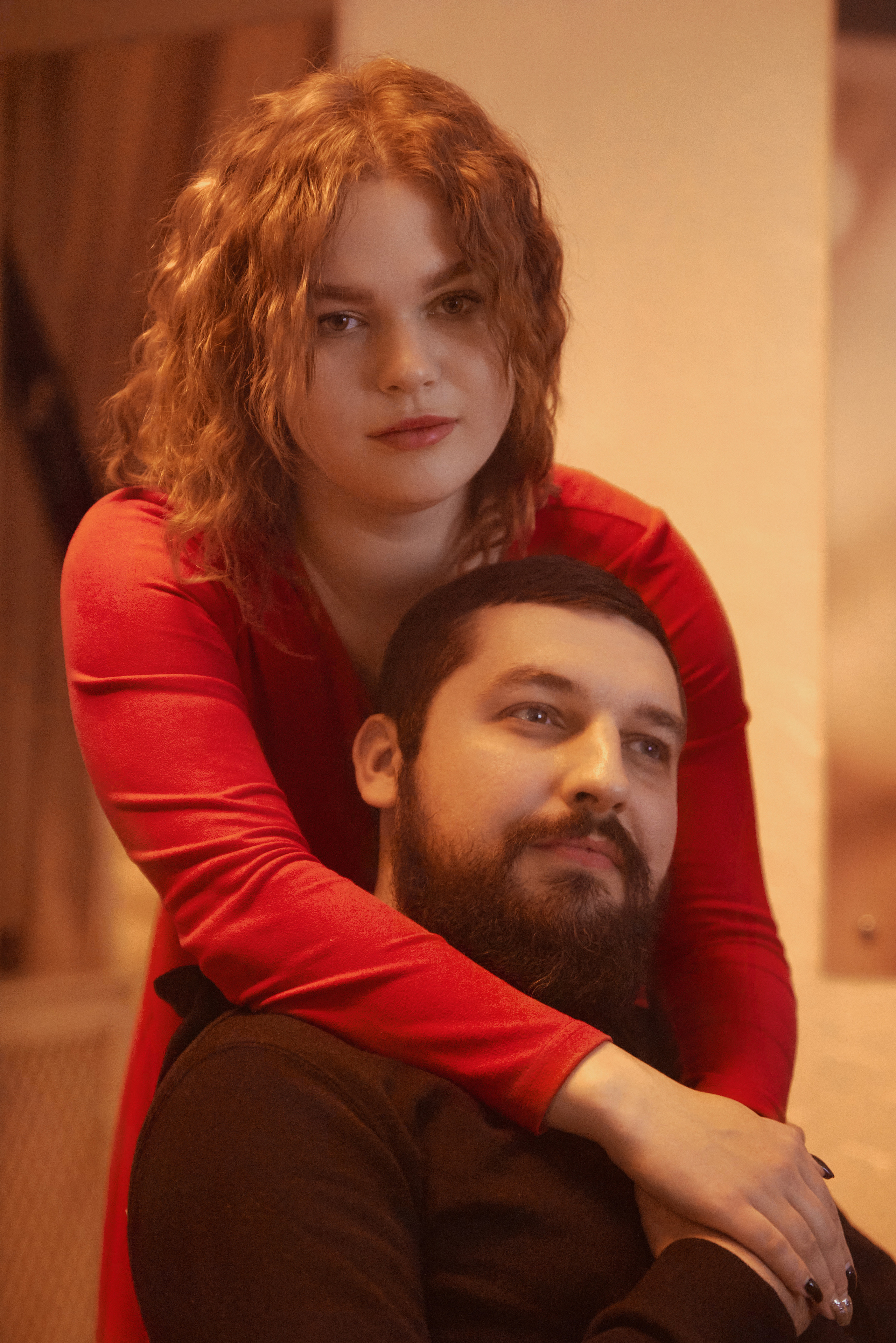 Девушка в красном платье и парень, обнимает за плечи.