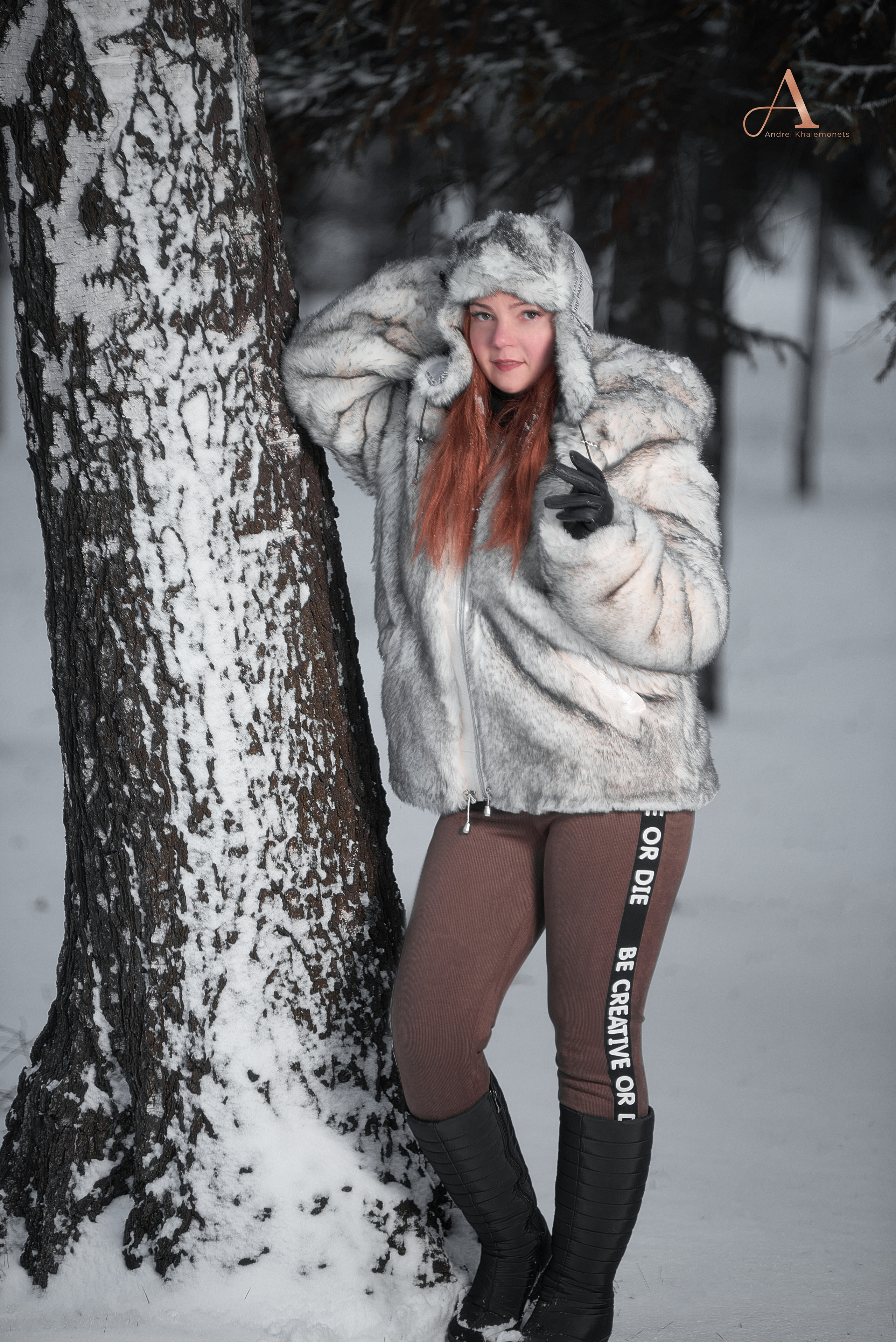 Девушка в белой шубе и меховой шапке у дерева.