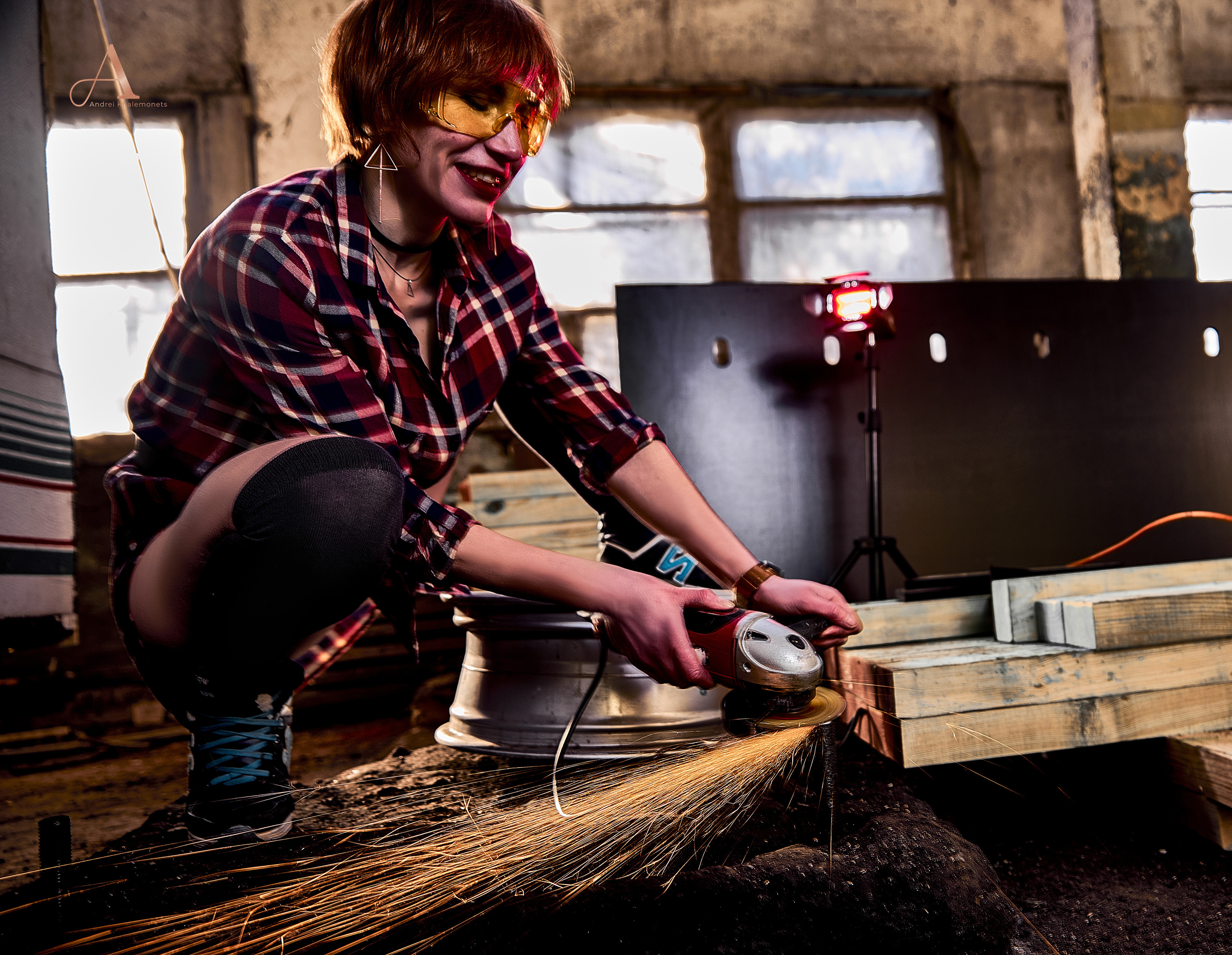 Рыжая девушка в черных гольфах работает с болгаркой, летящие искры.