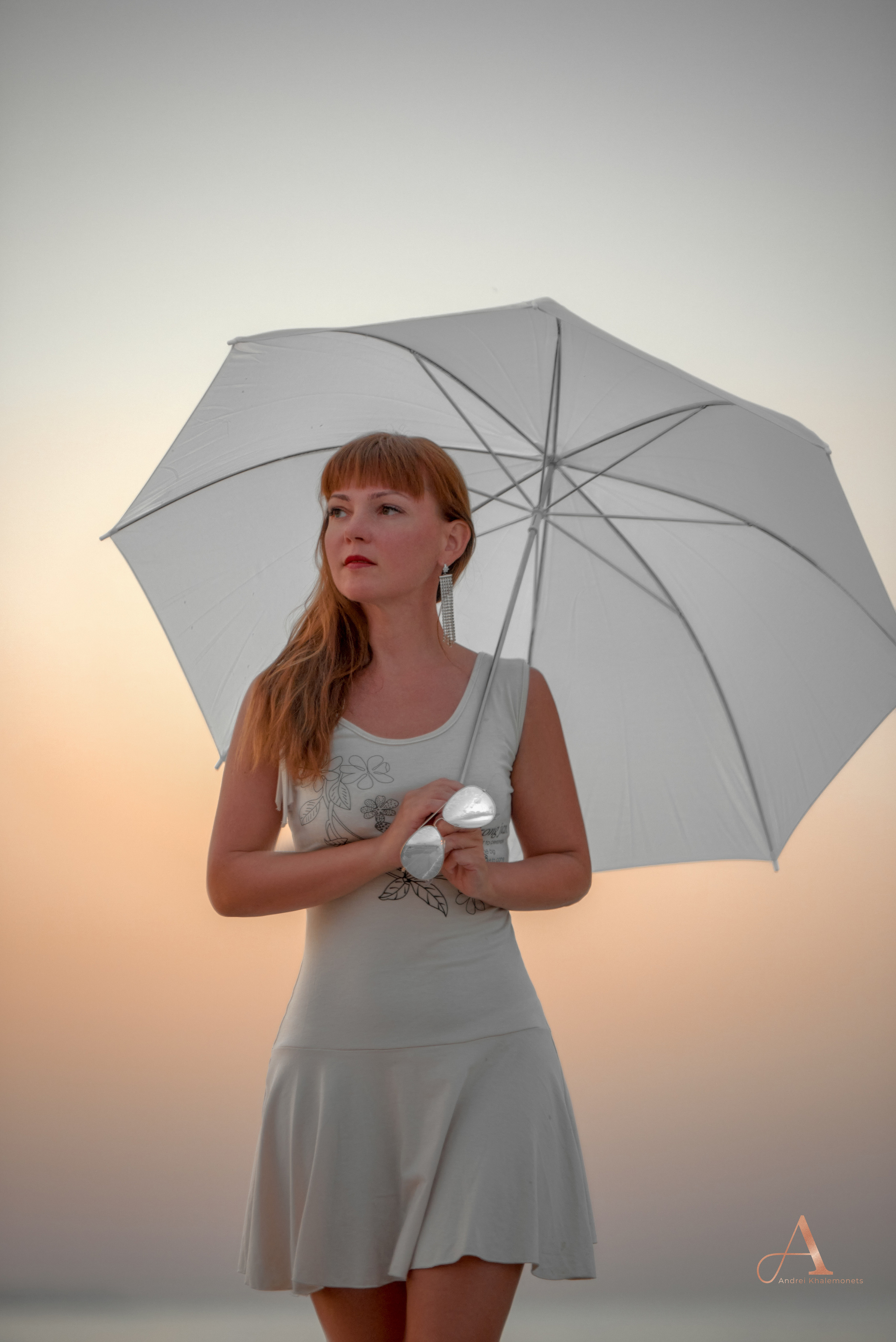 Девушка в белом платье на берегу моря с зонтиком.