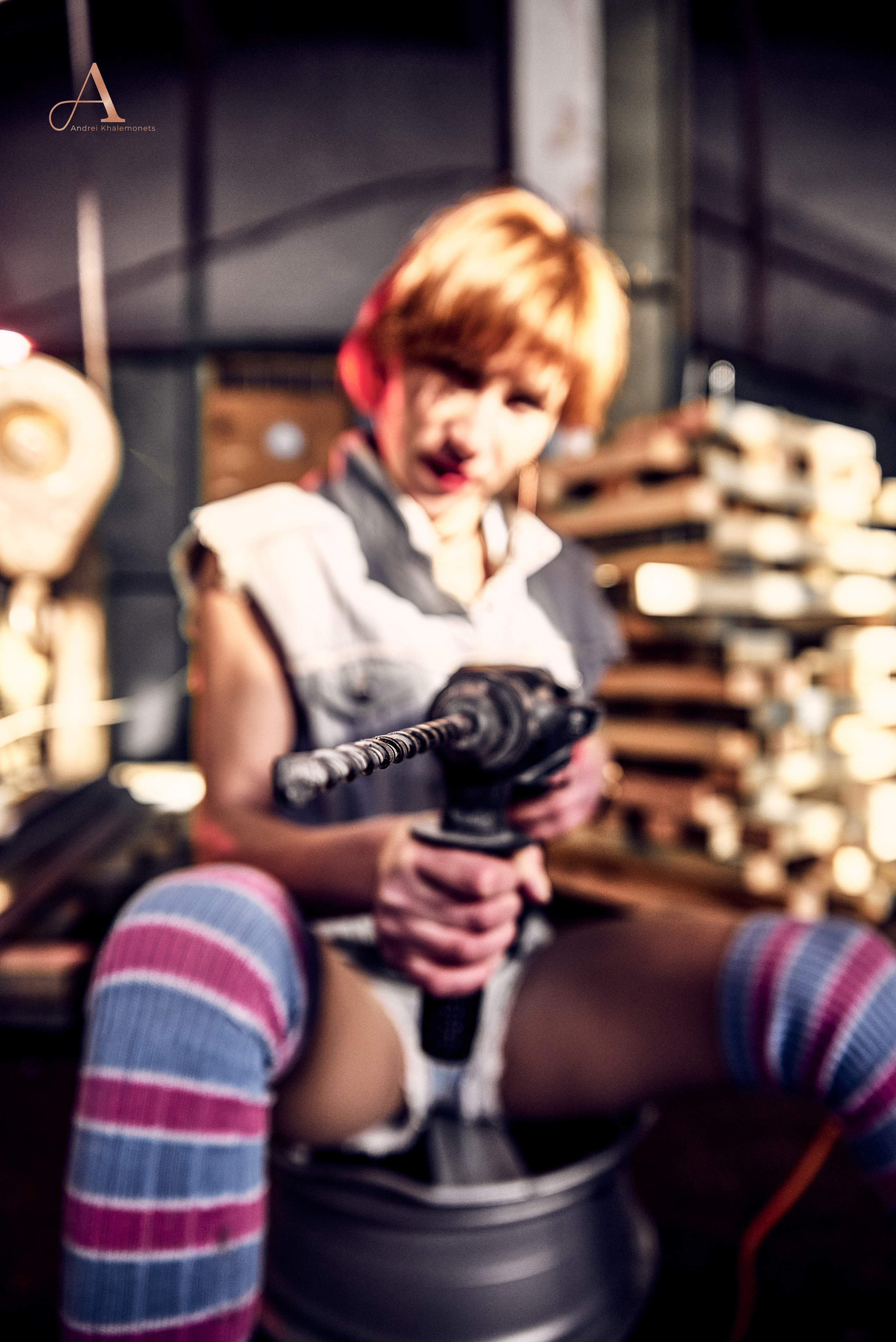 Девушка в мастерской с перфоратором в руках.