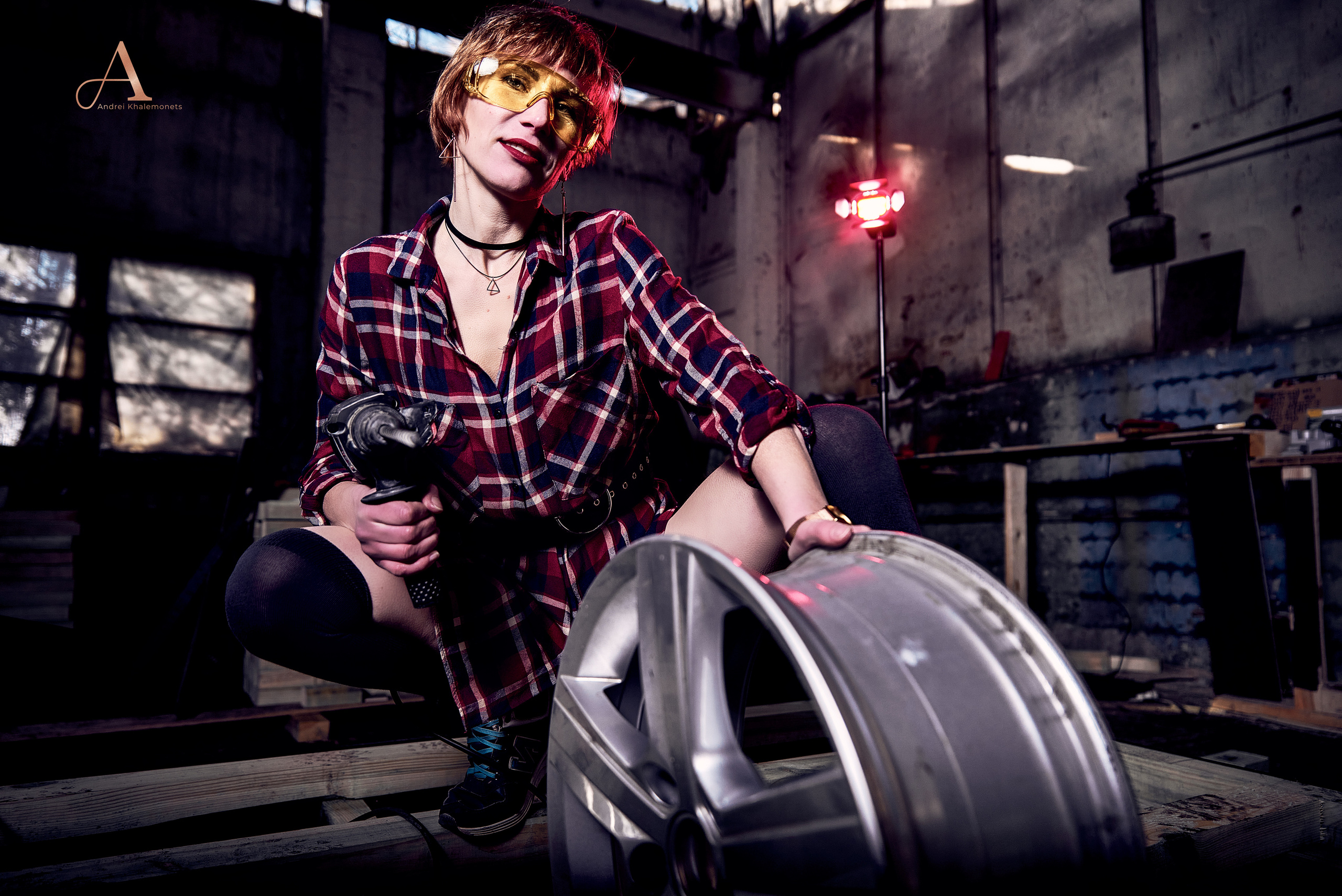 Девушка в черных гольфах и красной рубахе с перфоратором.