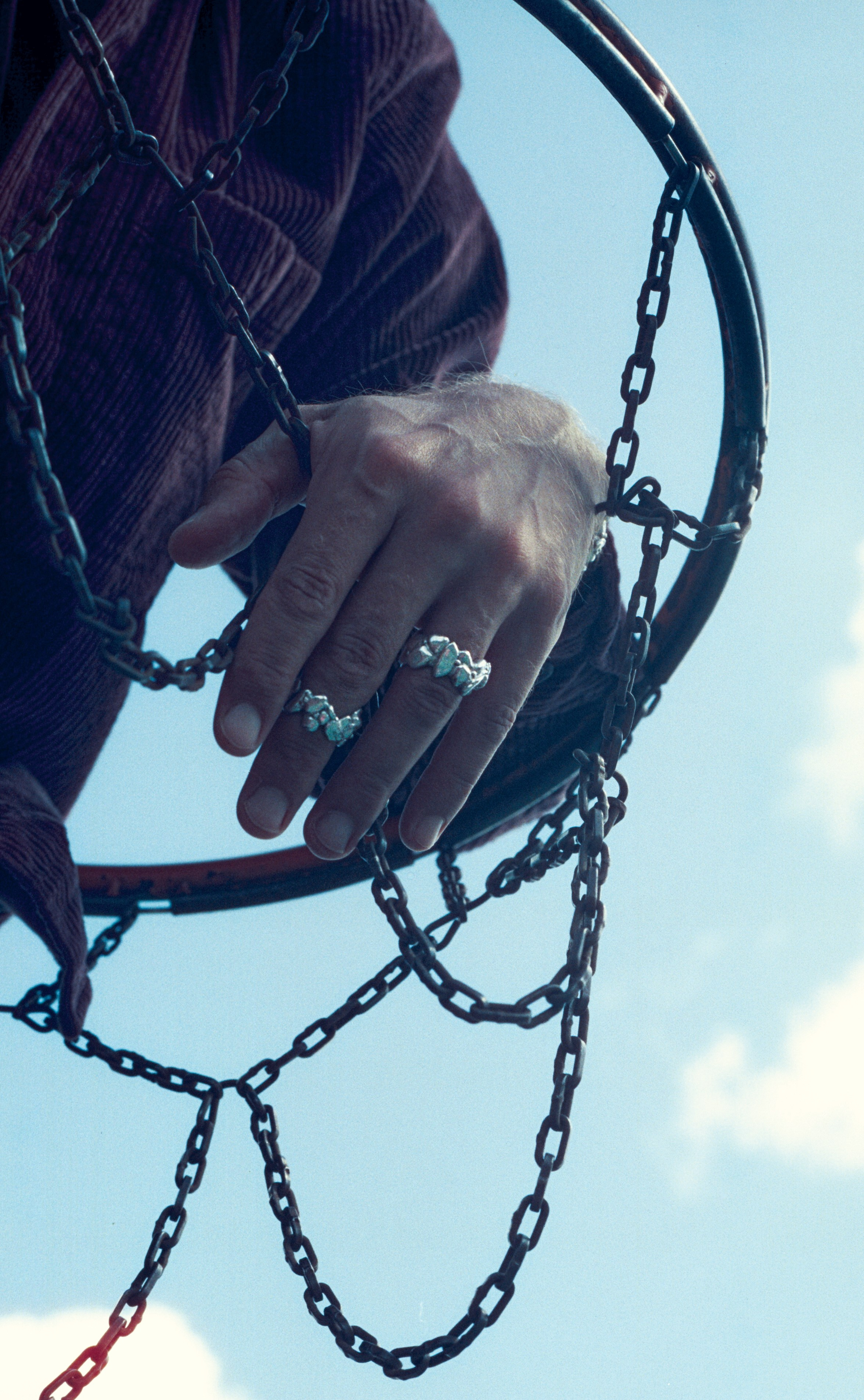Male model with a metal hoop wearing silver jewellery, movement-driven campaign photography for international jewellery brands, Cinestill 800t daytime