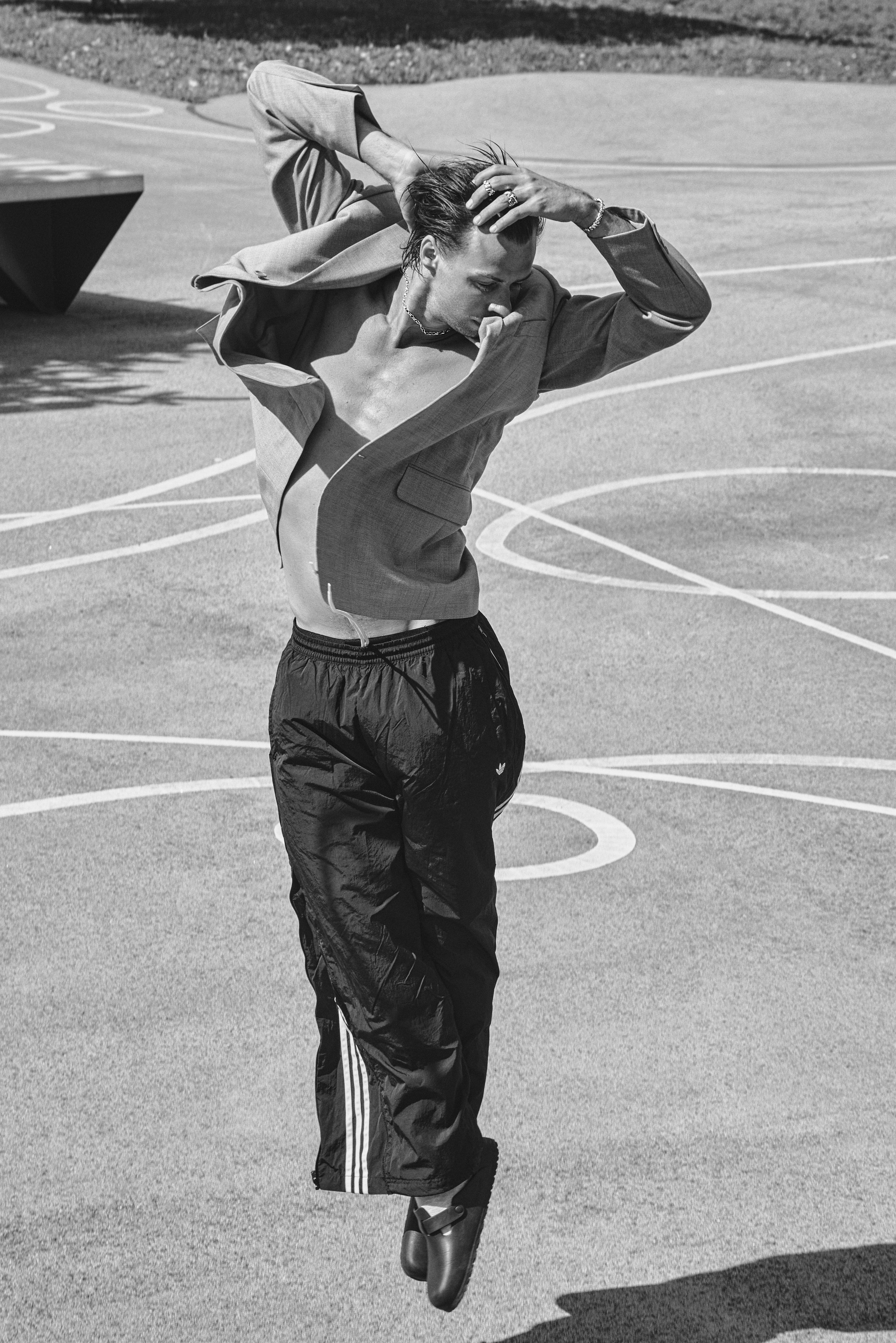 Black and white film portrait of a male model in motion, sportswear and jewellery editorial photography