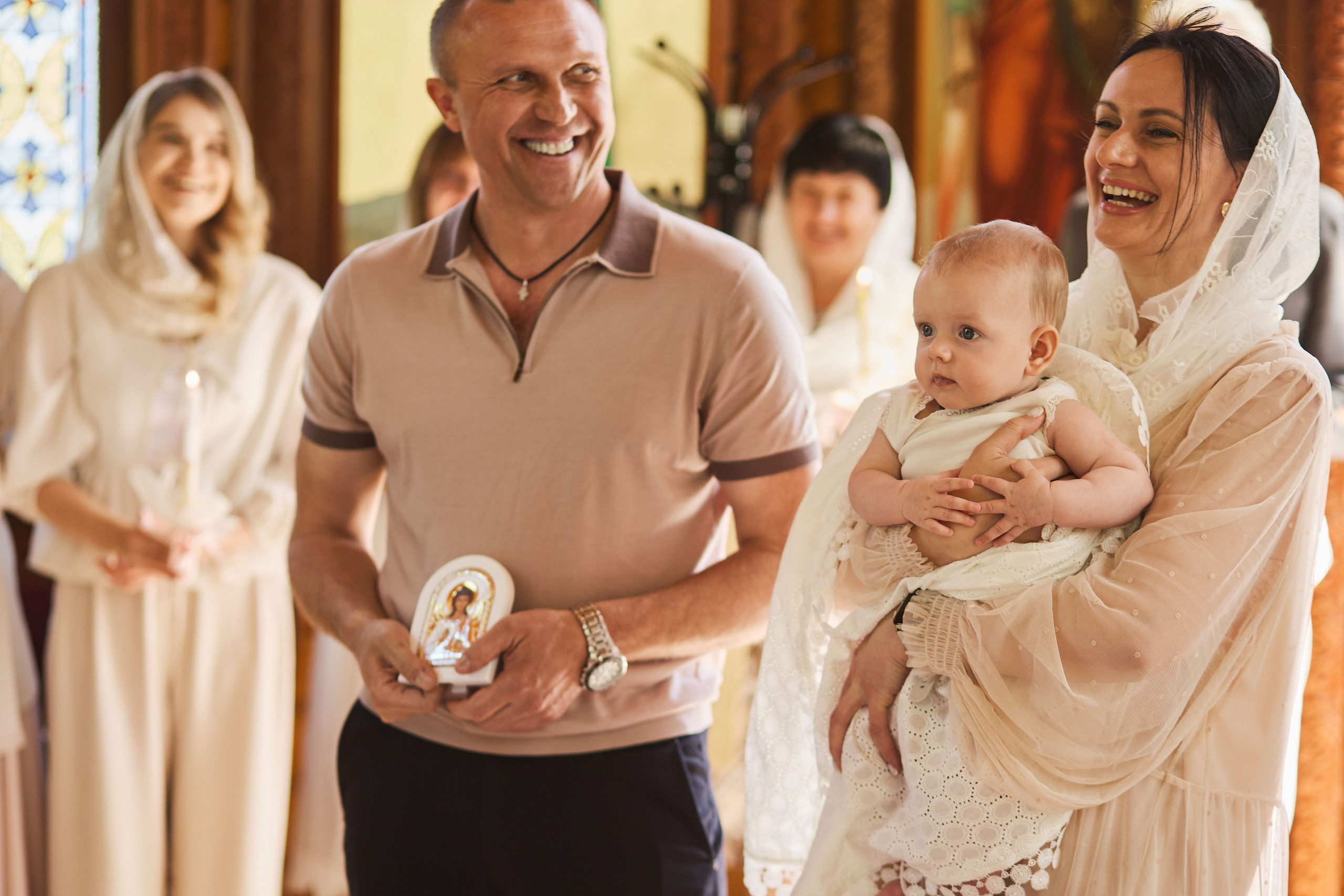 Сімейний момент на хрестинах у церкві, батьки з немовлям, фотограф