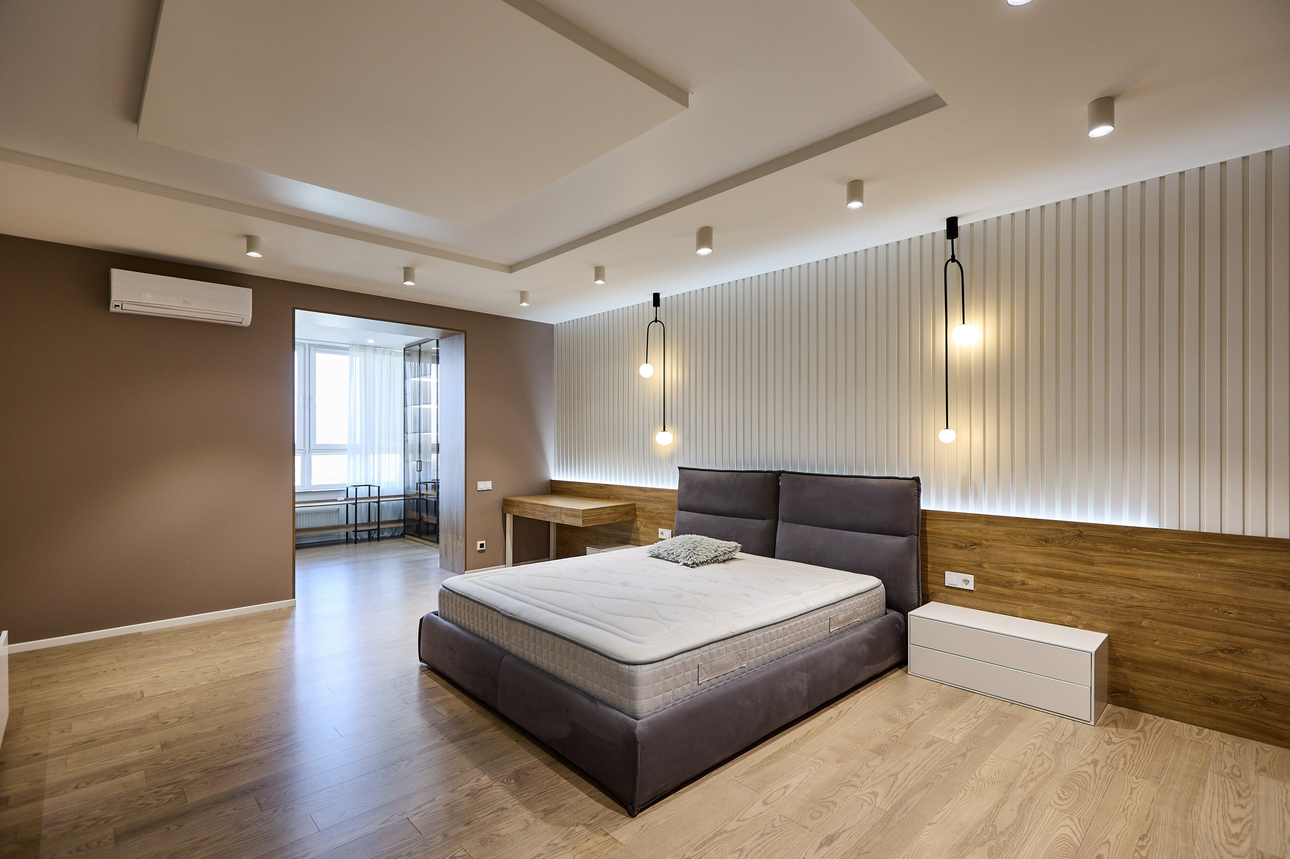 Фотограф в Днепре запечатлел интерьер спальни с современным дизайном, кровать с серыми подушками и светодиодным освещением на стенах.