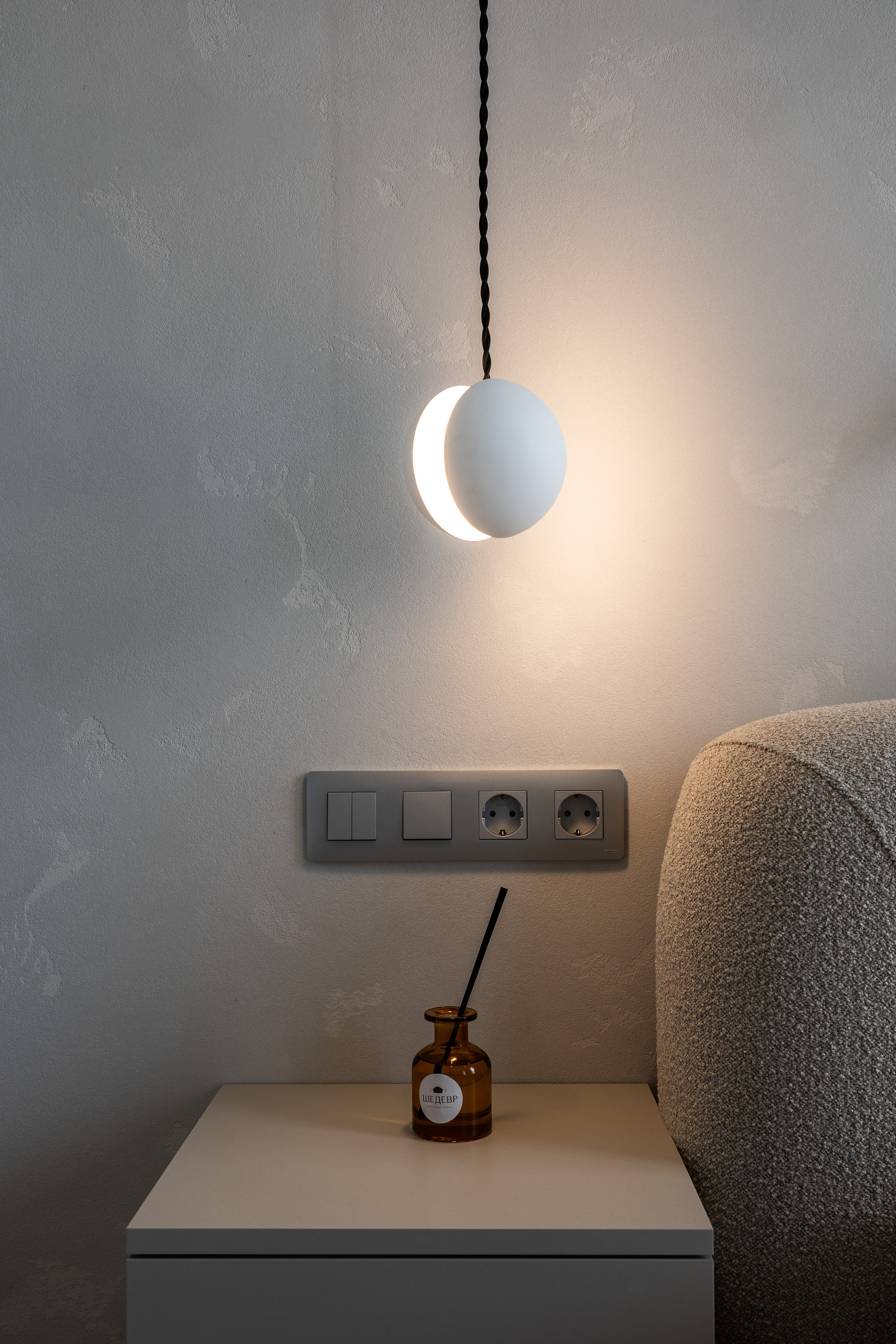 Настінний світильник біля ліжка на сірій стіні, фотограф Дніпро.