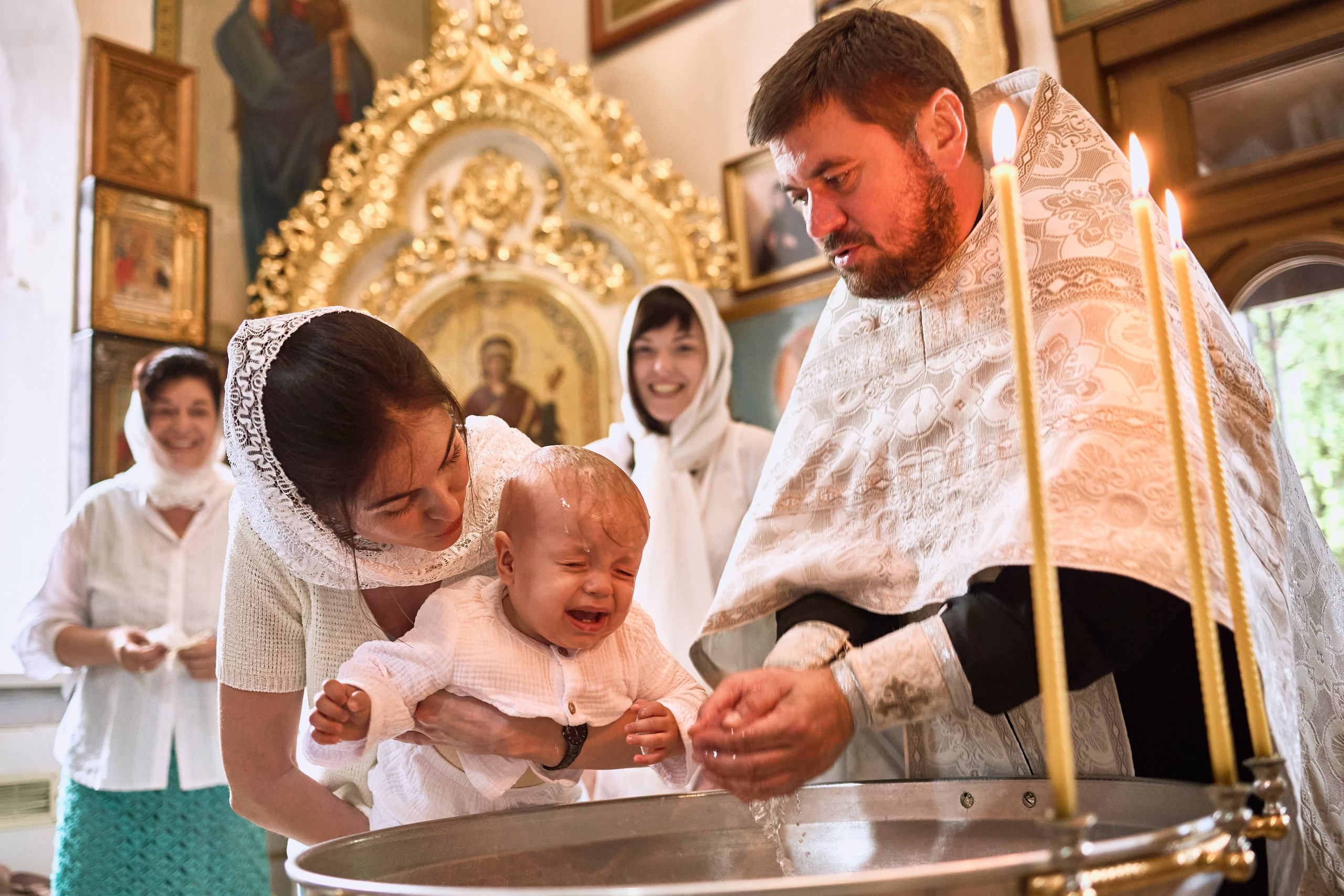 Обряд хрещення біля купелі — мама з дитиною та священник