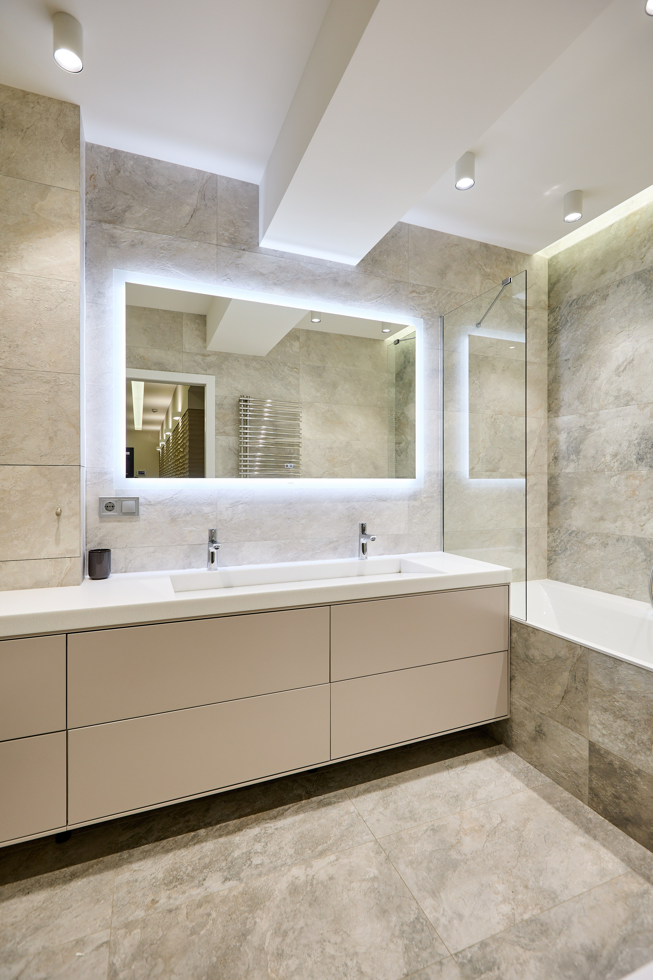 Современный интерьер спальни в Днепре — кровать с серым изголовьем и стильный деревянный столик у стены с перегородкой.