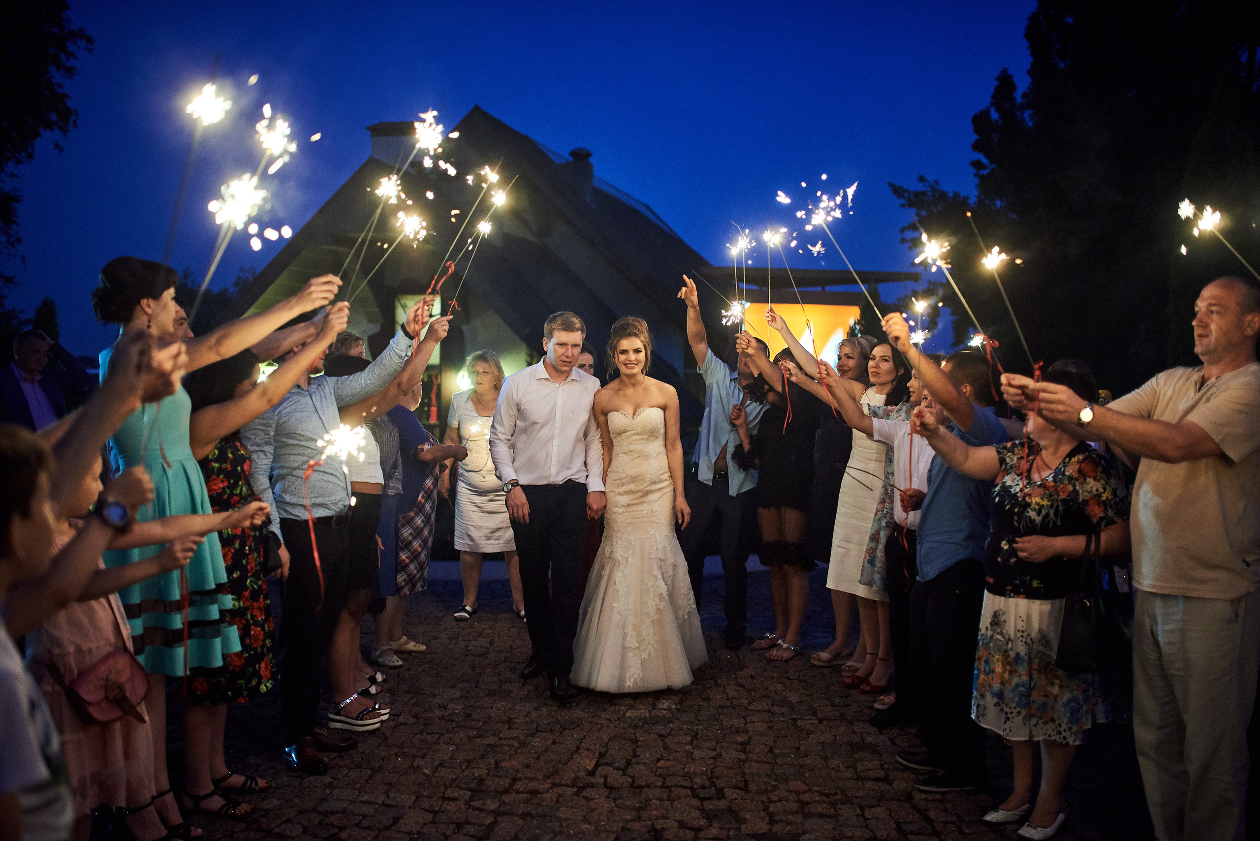 Фотограф Дніпро зафіксував ніжну весільну фотосесію, де наречена в білому платті тримає квіти, а наречений усміхається поруч.