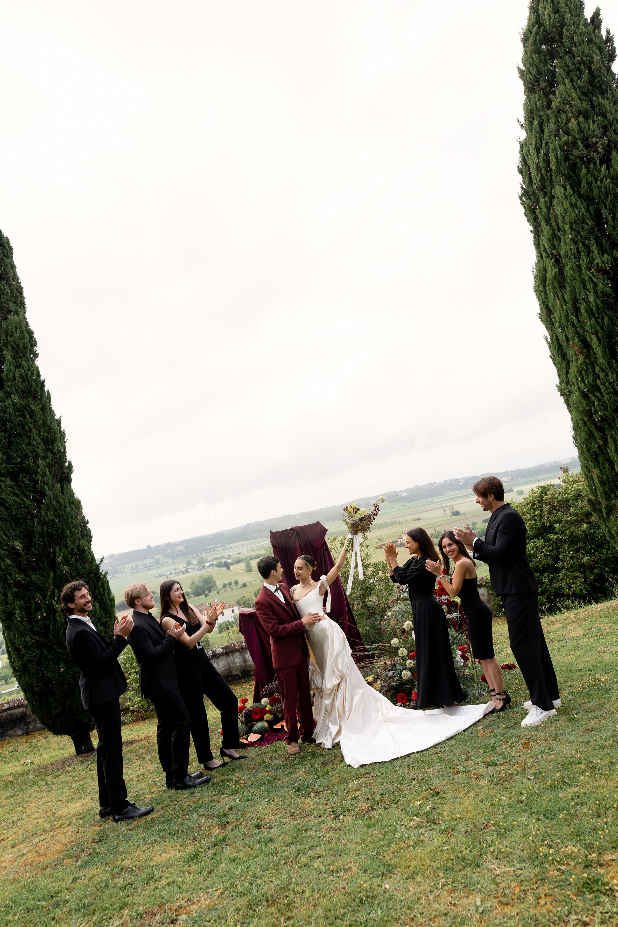 Bride in Tuscany near cypress trees on a cloudy wedding day. Elegant Italian wedding atmosphere photographed by Elena Marshall Photo.