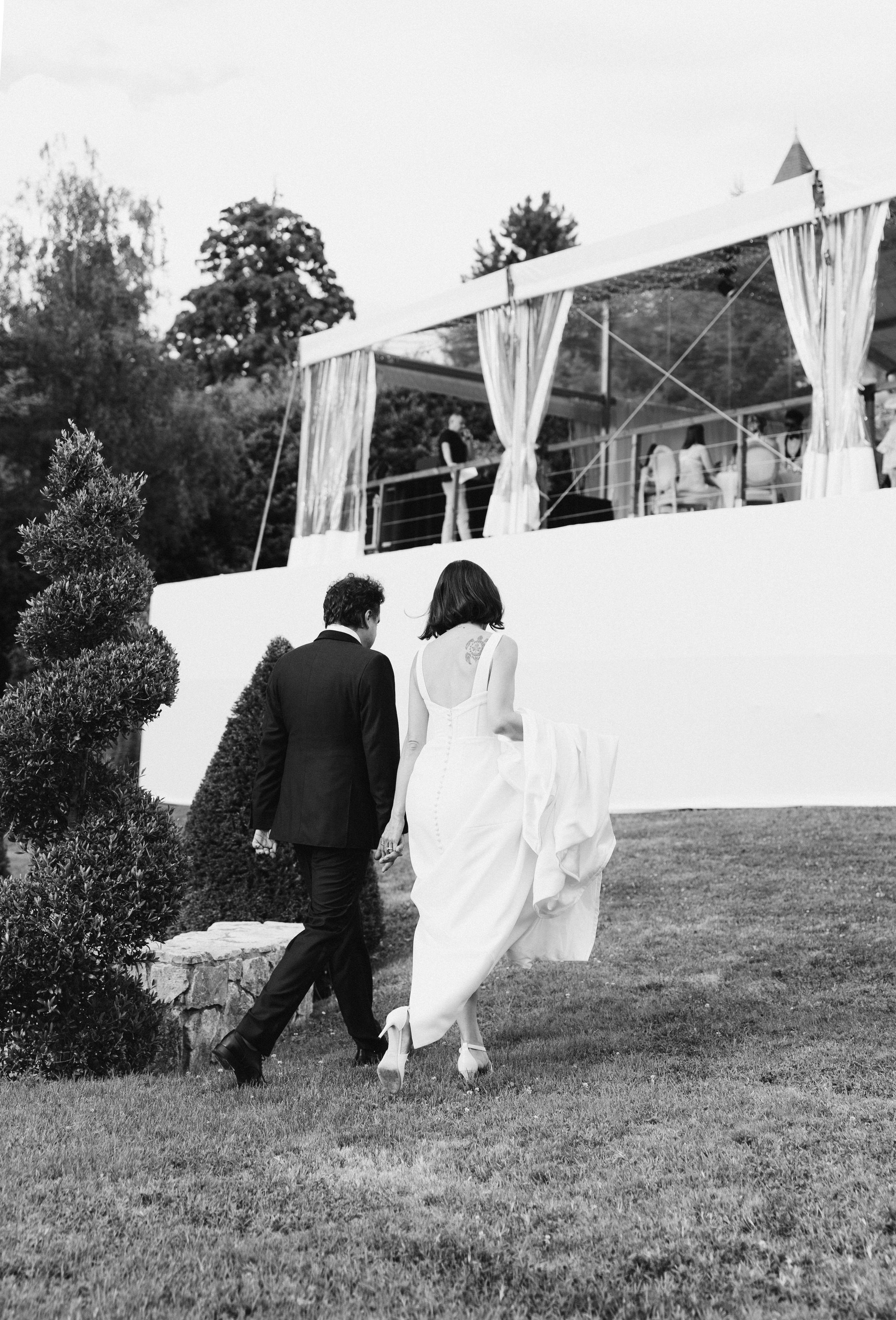 Black and white candid photo of newlyweds walking after wedding ceremony