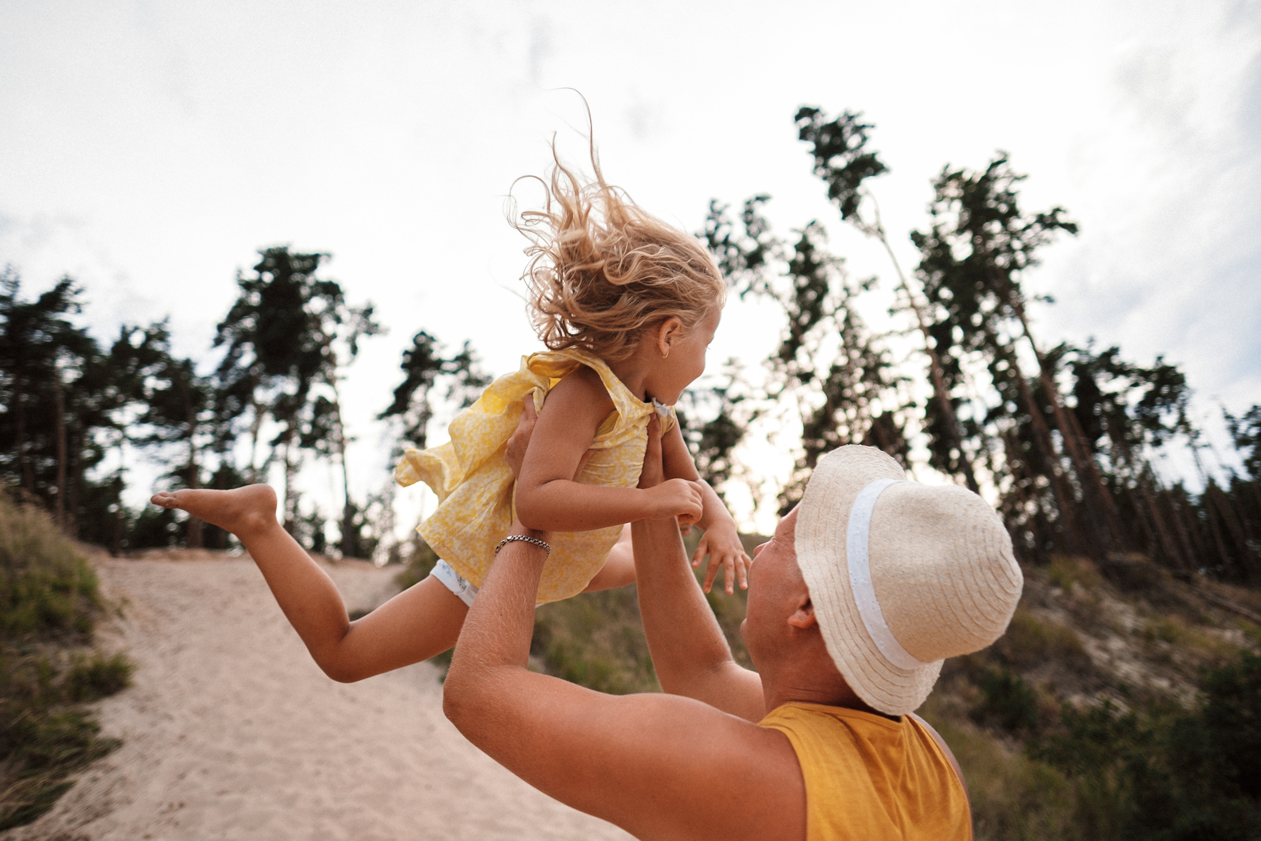 папа подбрасывает дочку, разлетаются волосы