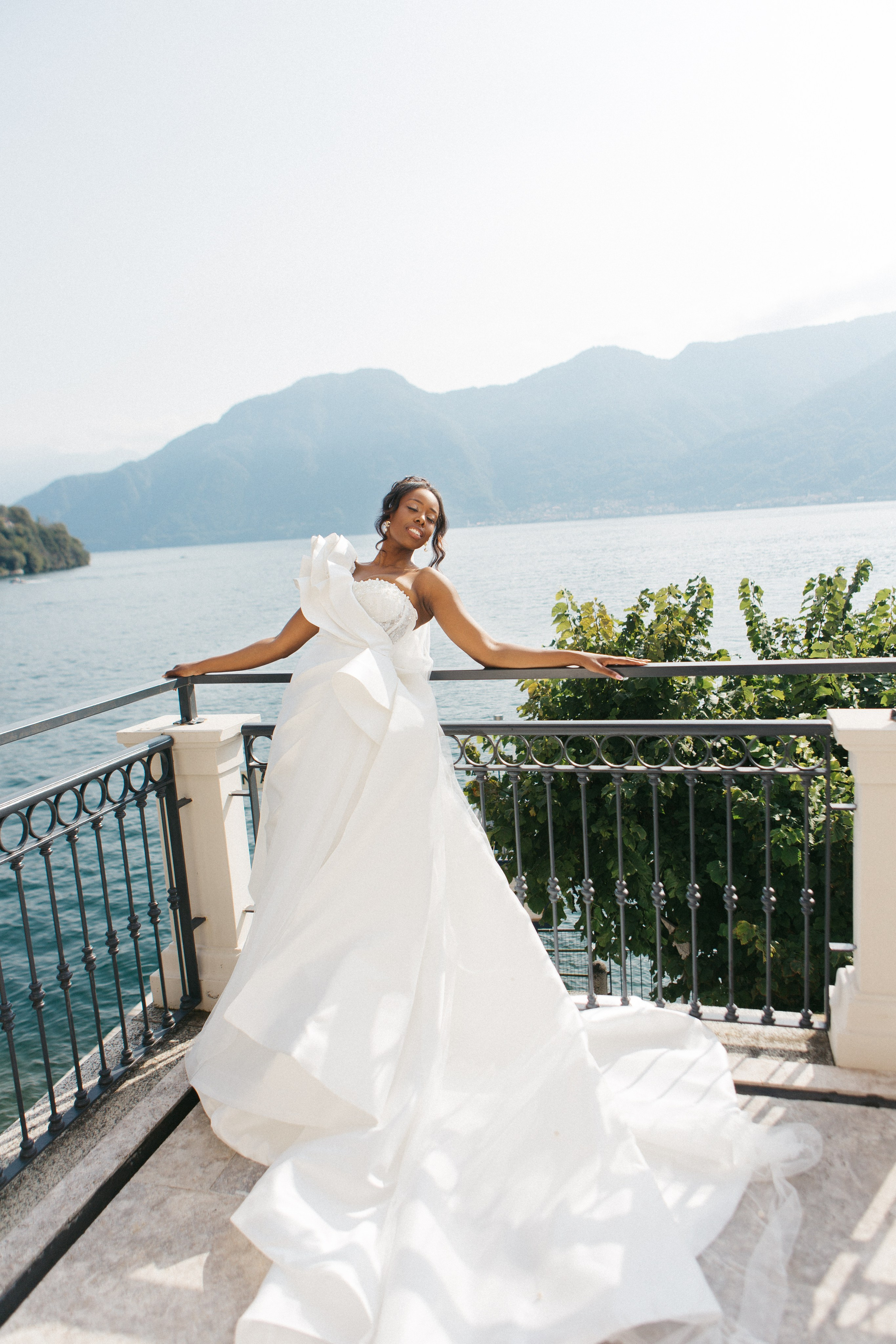 Elegant fashion portrait of a dark-skinned bride overlooking scenic Lake Como, highlighting modern bridal style