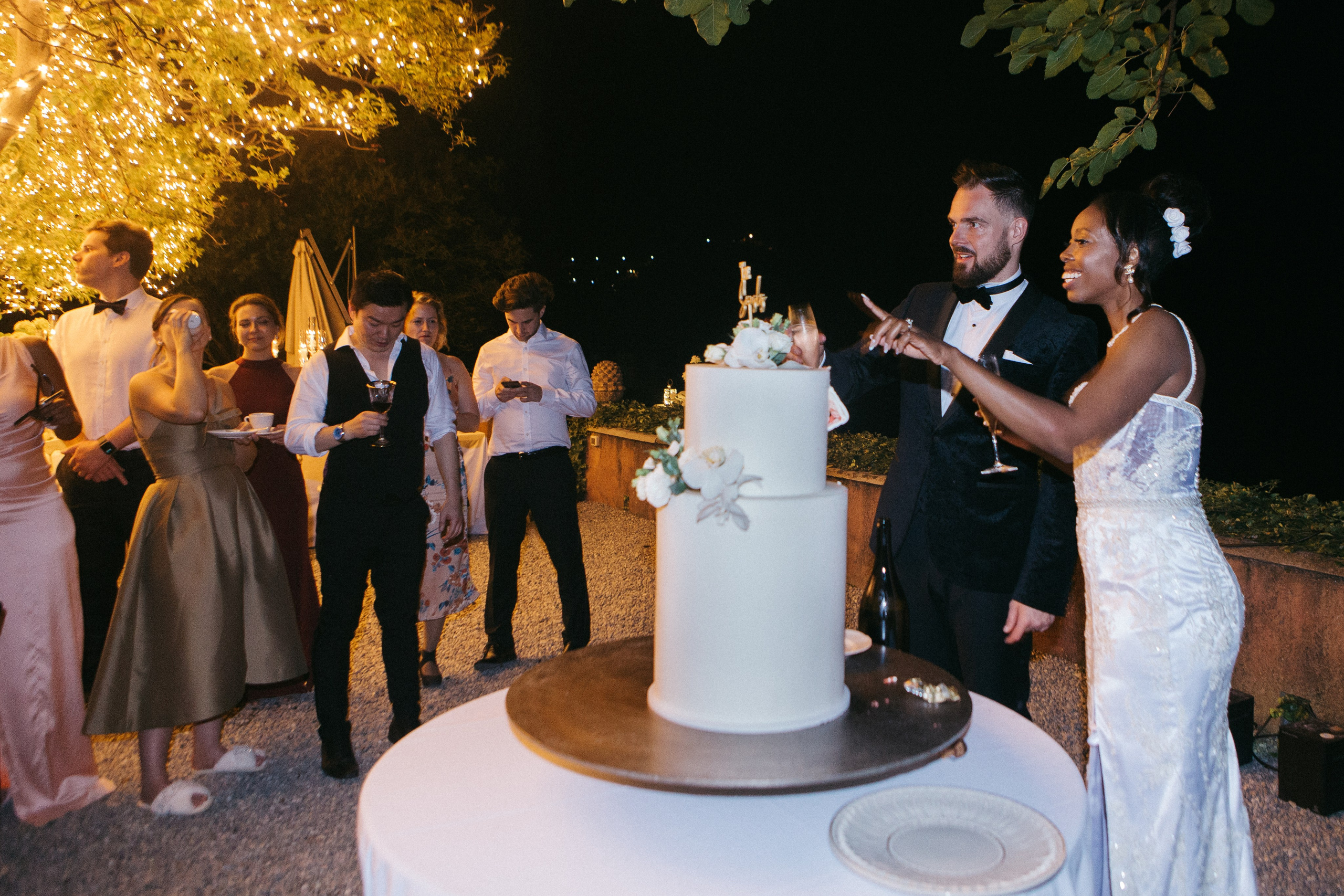 Joyful moment of the bride and groom cutting their wedding cake, surrounded by the magical light of candles during the wedding in Como lake 
