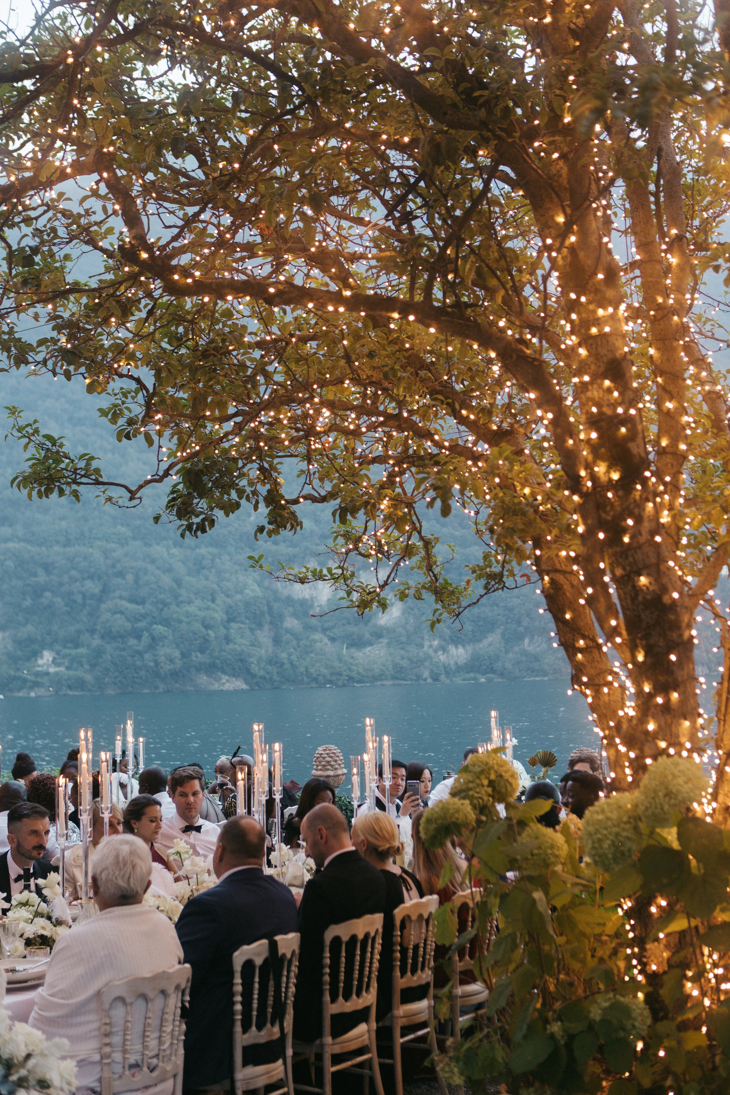 Elegant wedding scene of guests enjoying the blue hour, with soft candlelight creating a magical atmosphere at Lake Como in Villa Regina Teodolinda 