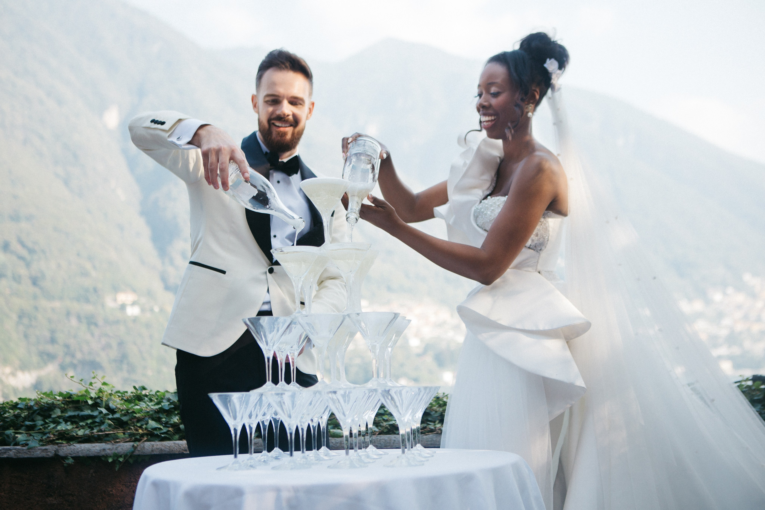 Happy couple creating a champagne tower at their wedding reception at Villa Regina Teodolinda in Como lake 
