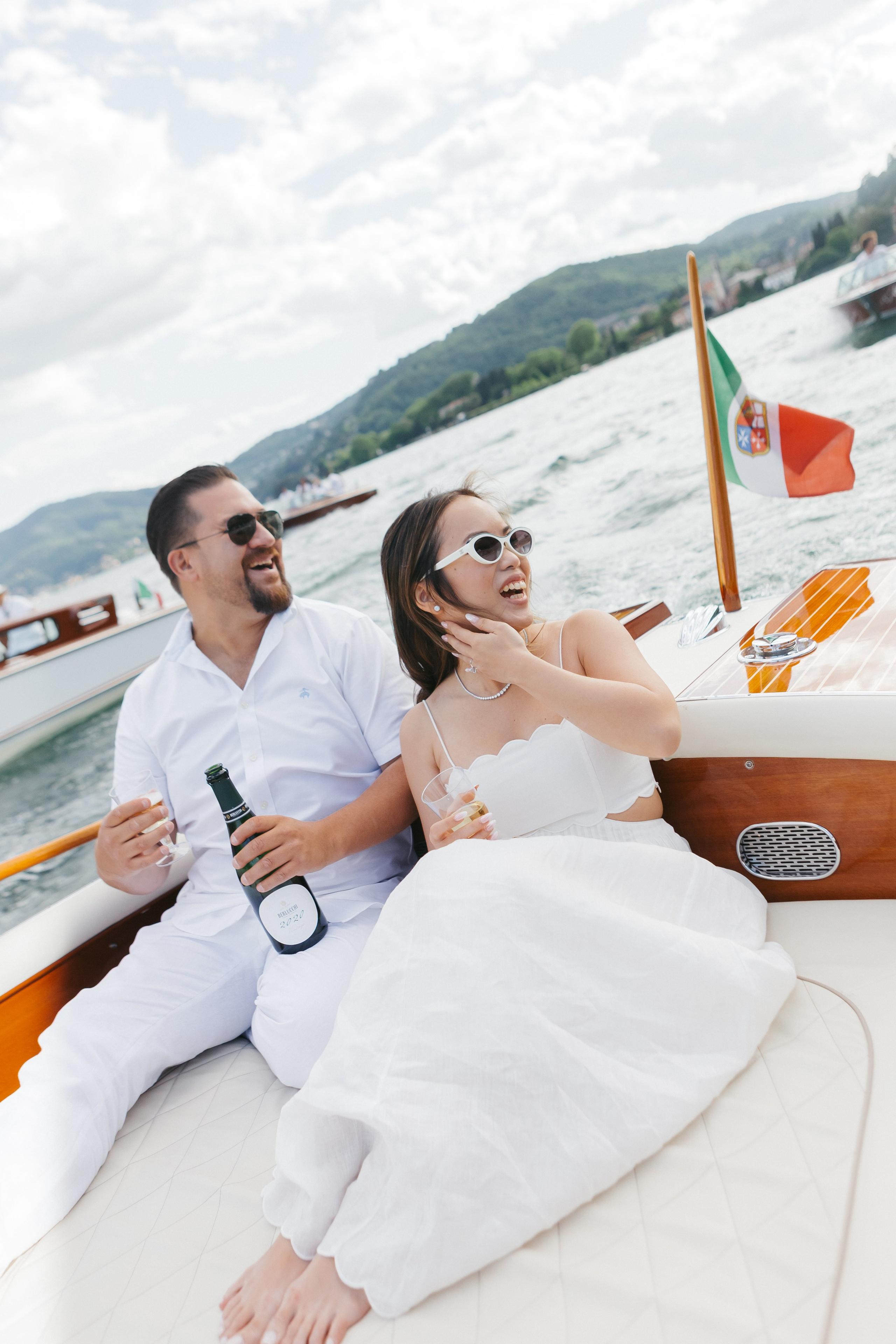 Fashionable couple in white enjoying a pre-wedding boat party on Lake Como