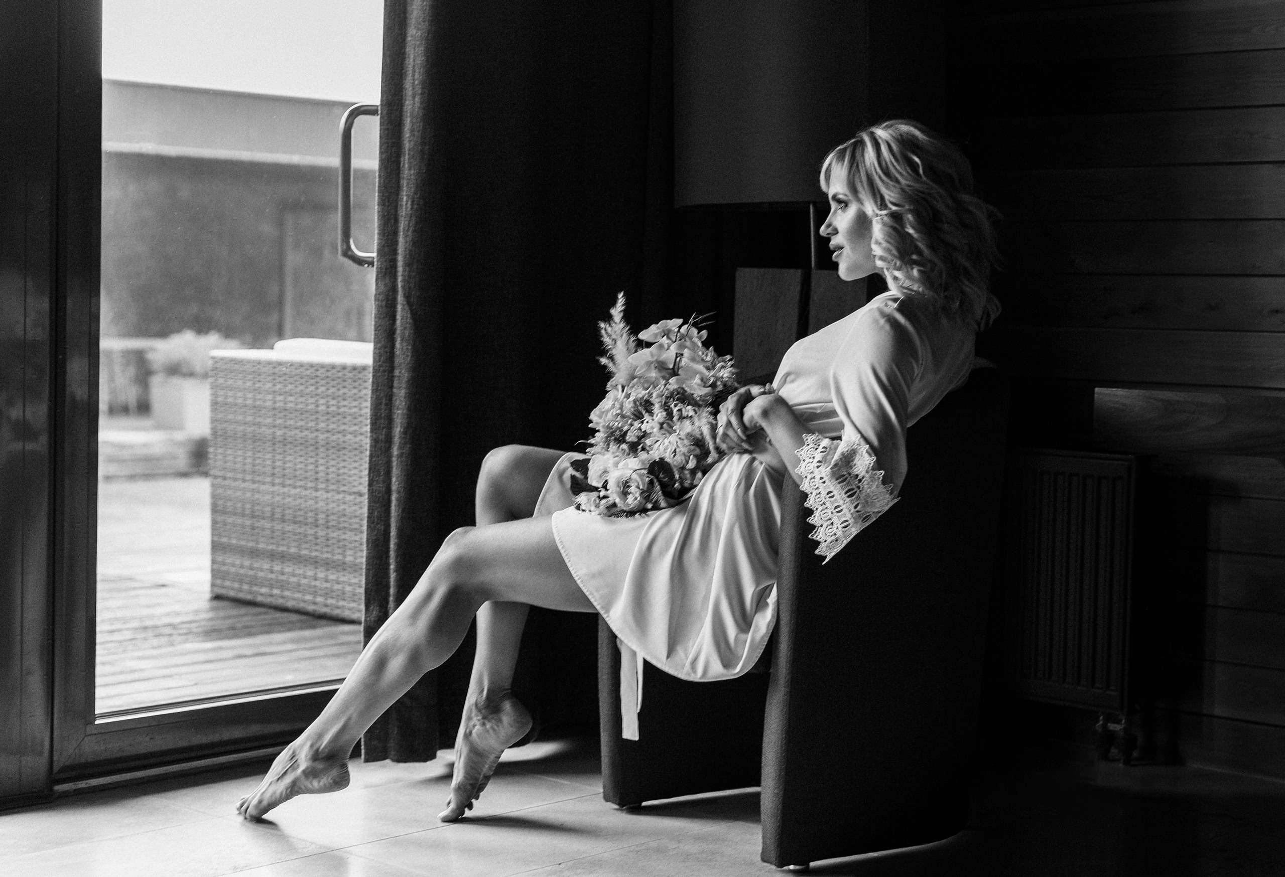 невеста в халате сидит на стуле и смотрит в окно