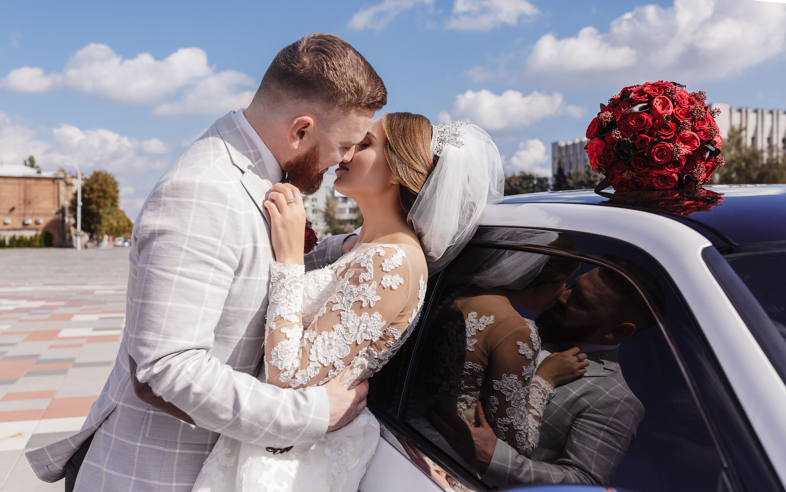 жених обнимает невесту возле машины в зеркале видно их отражения