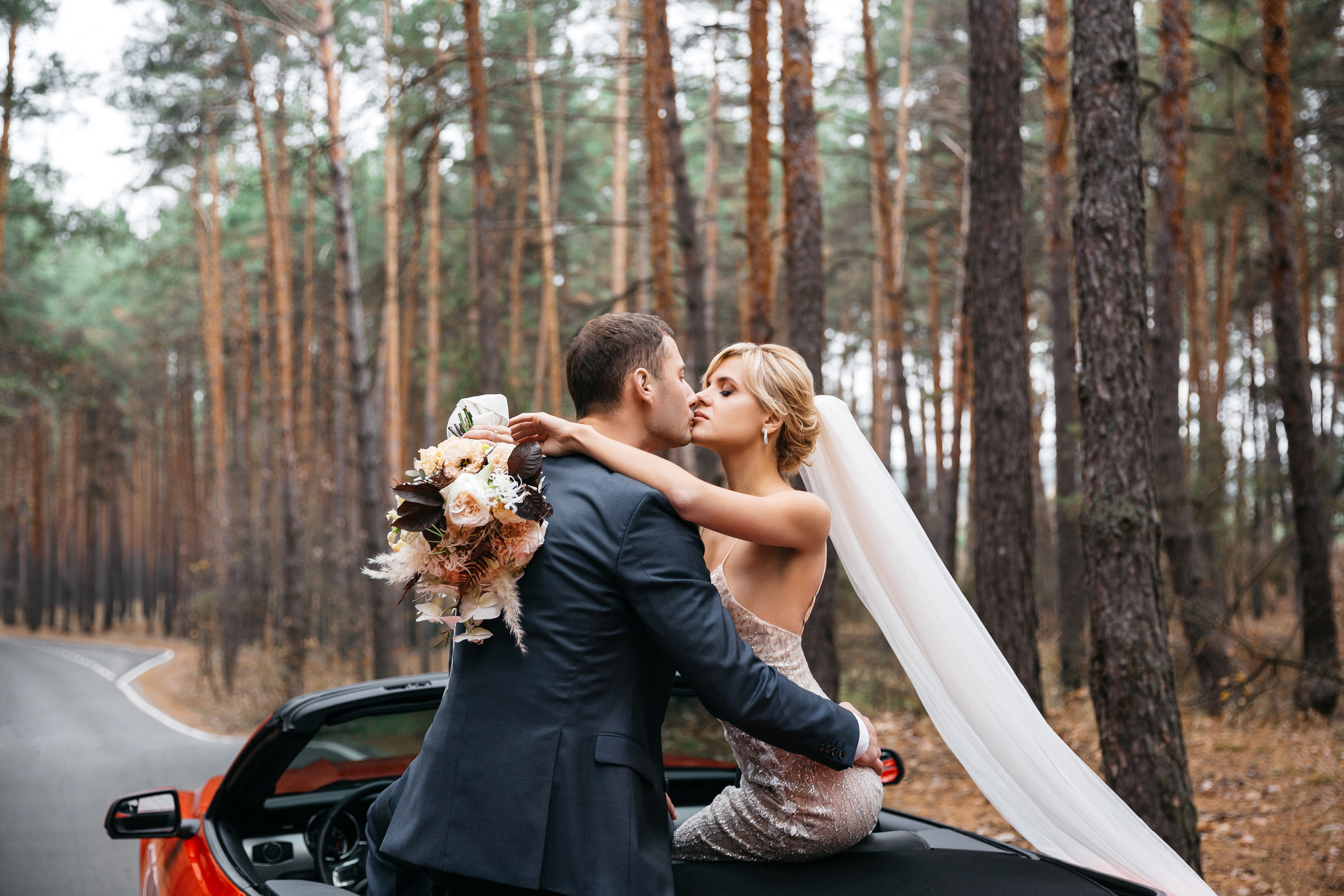 жених целует невесту во время свадебной прогулки