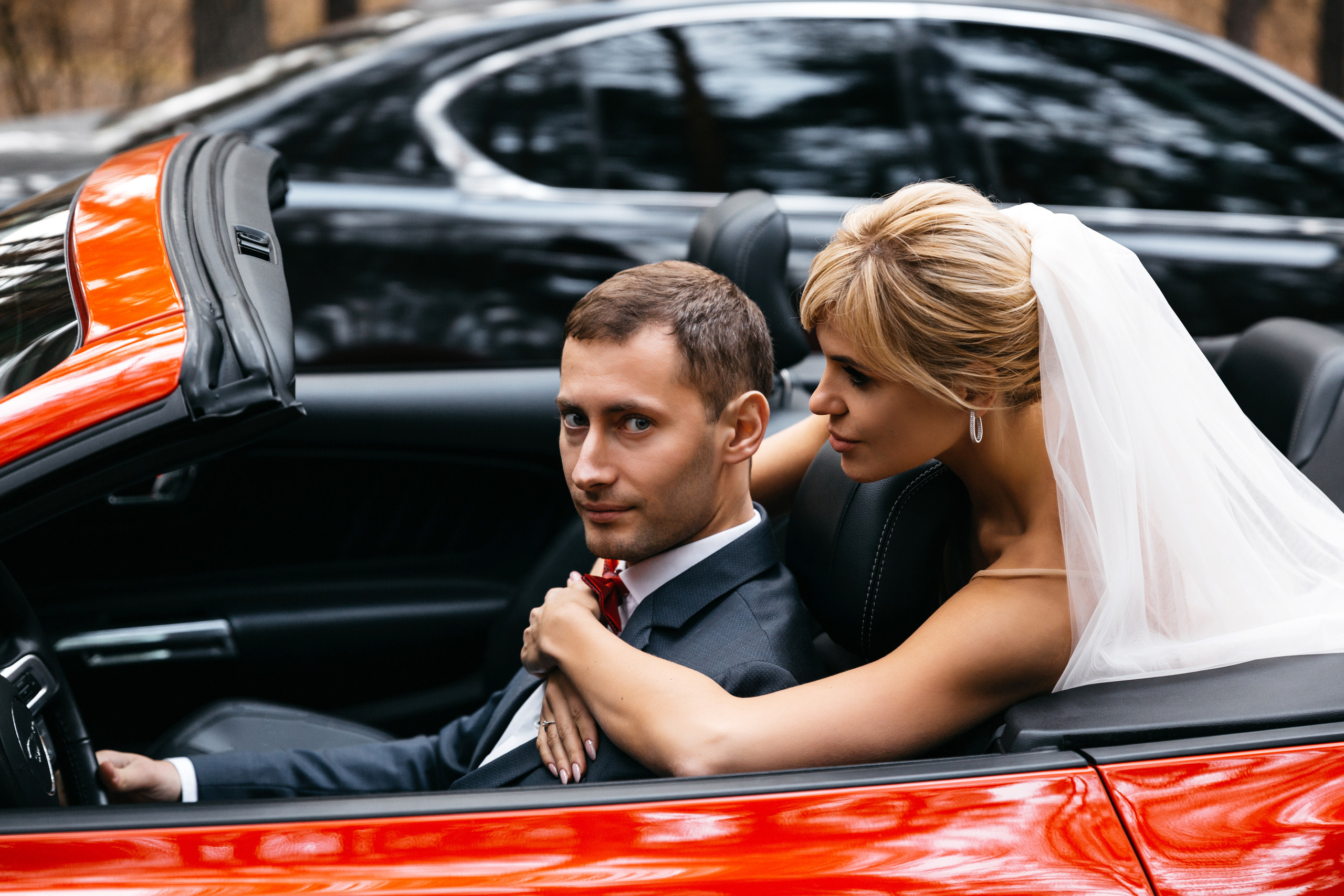 невеста обнимает жениха за шею в машине
