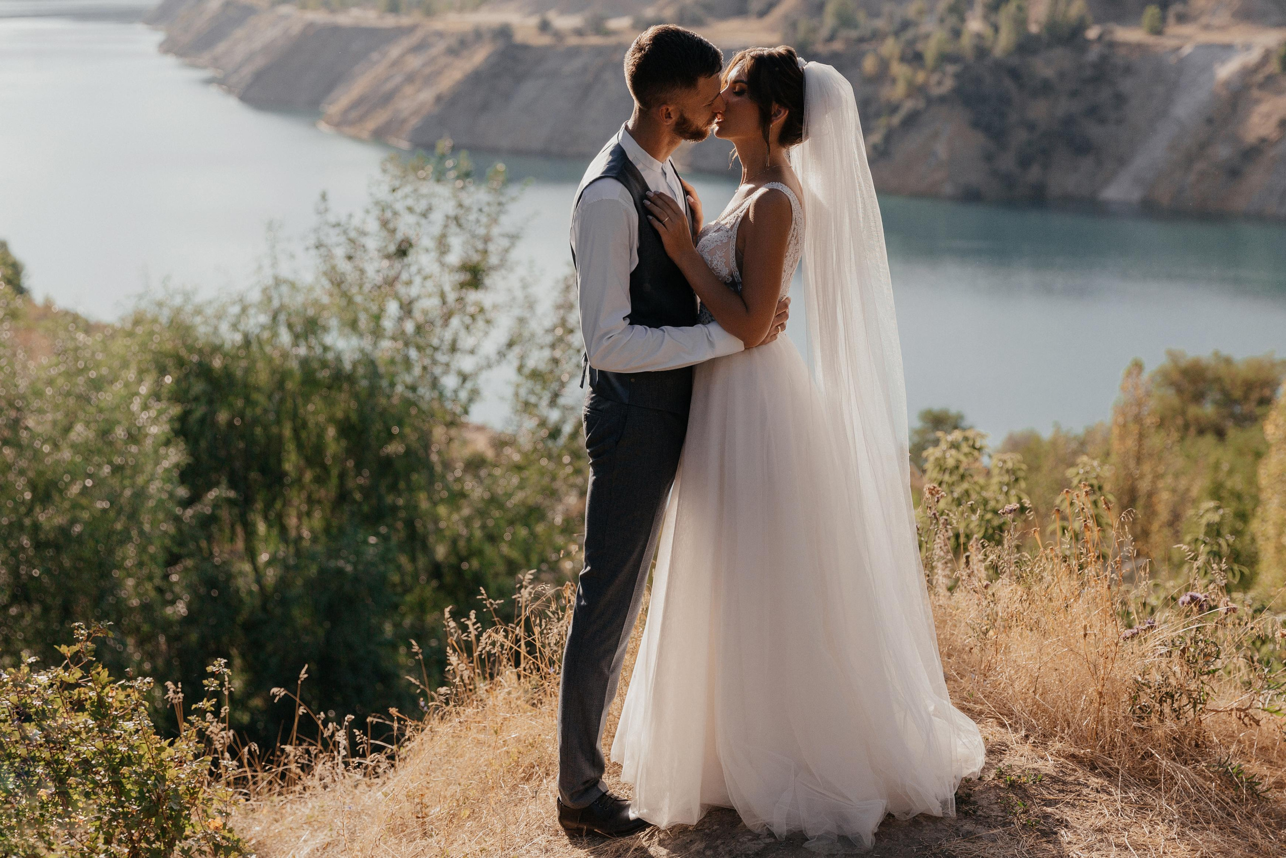 пара на свадьбе в контровом свете позирует на фоне реки и природы