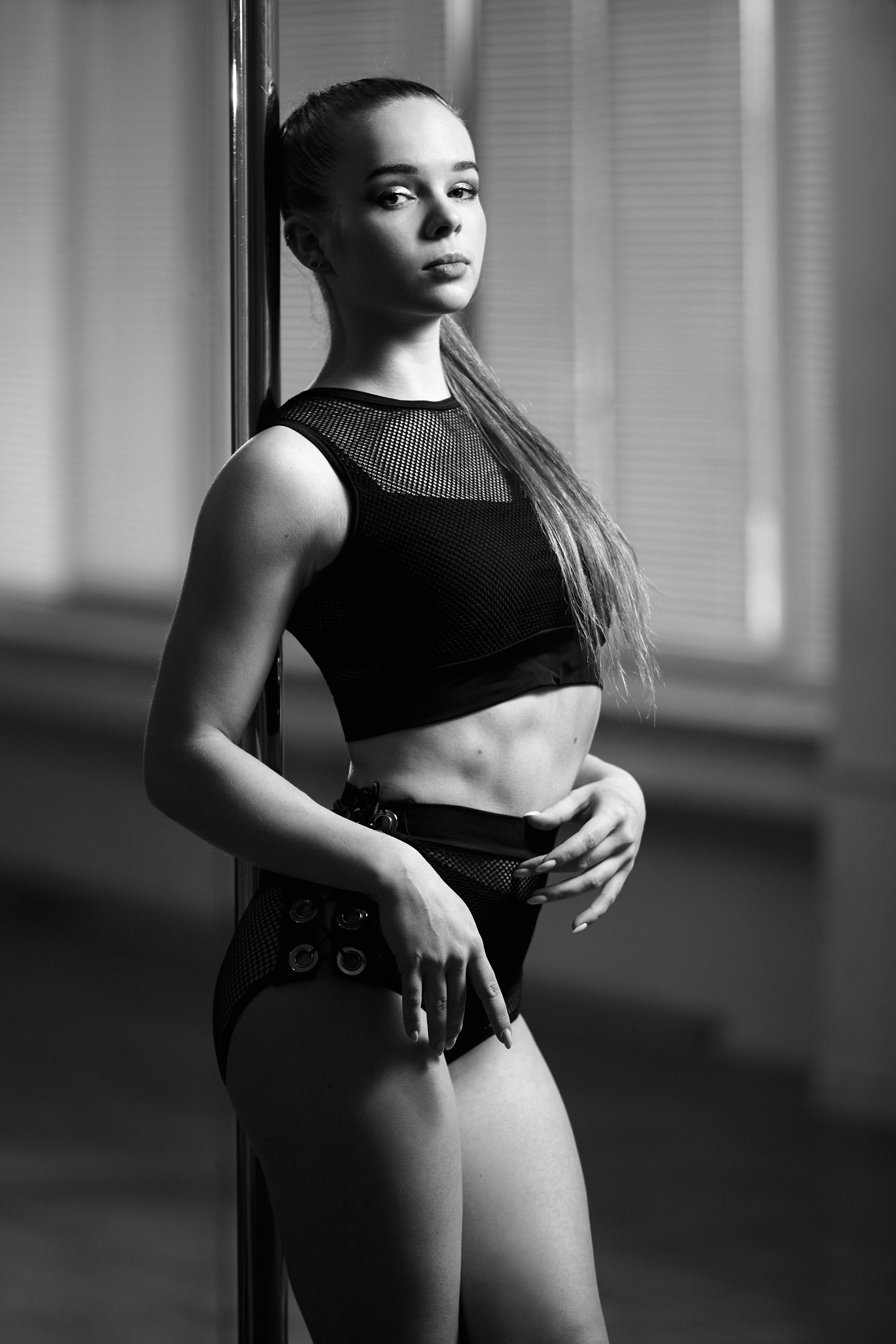 Чорно-білий кадр танцівниці біля пілону, акцент на рухах та обличчі