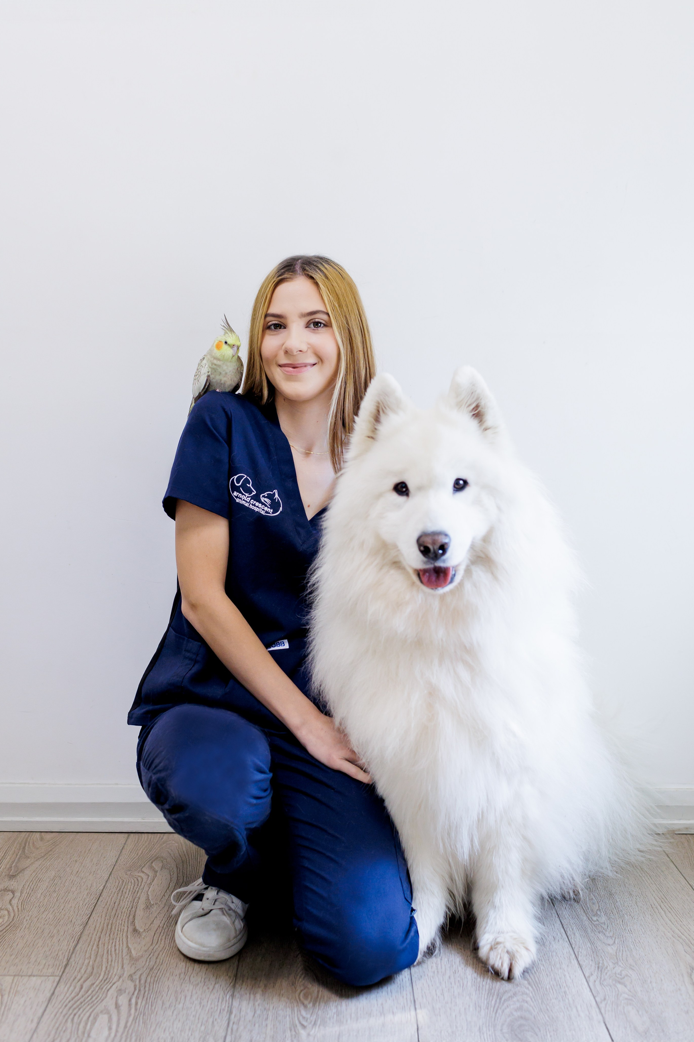Natural headshot of a female veterinary practice owner with warm, professional hair and makeup, Posing with her own pets