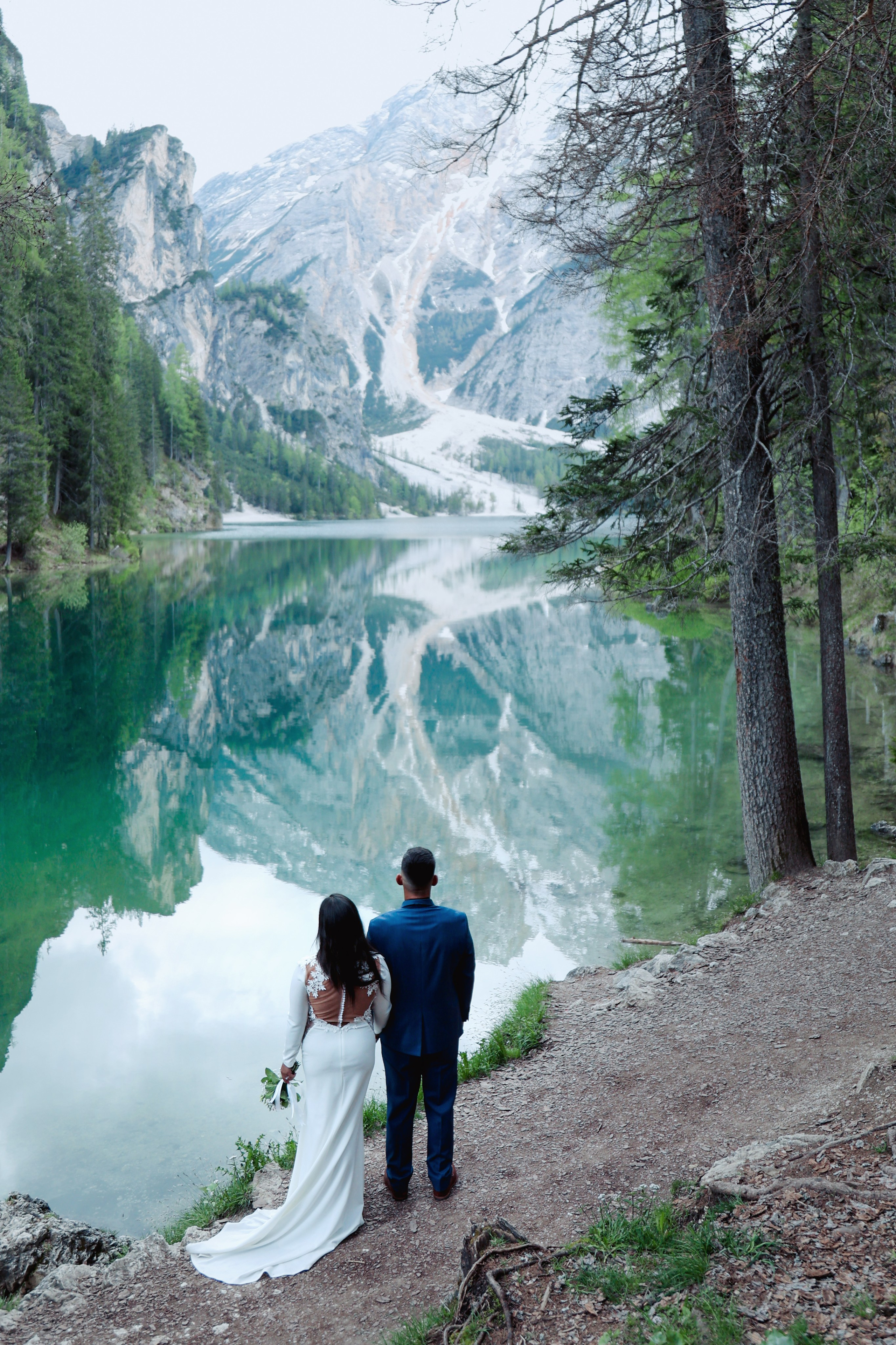 Bride and groom walking by Lake Braies during their Dolomites elopement
