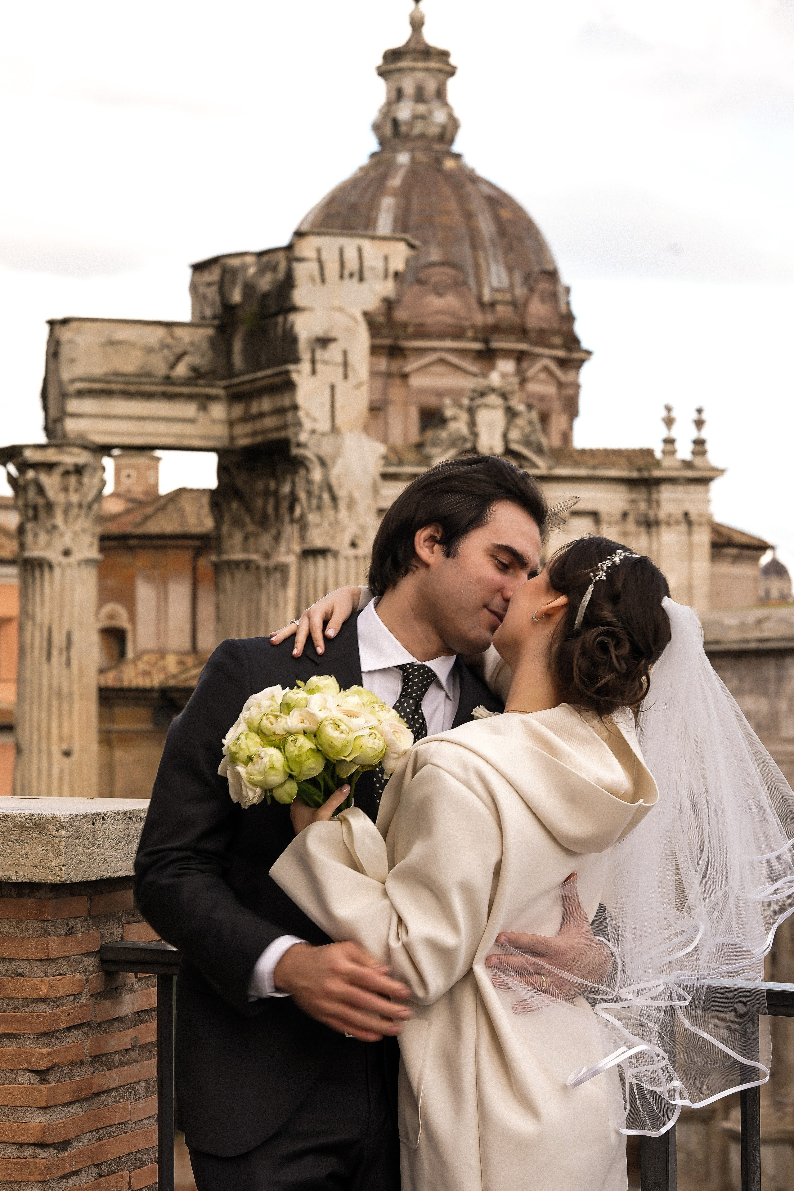 Bride and groom kissing against Roman ruins — wedding photography in Rome