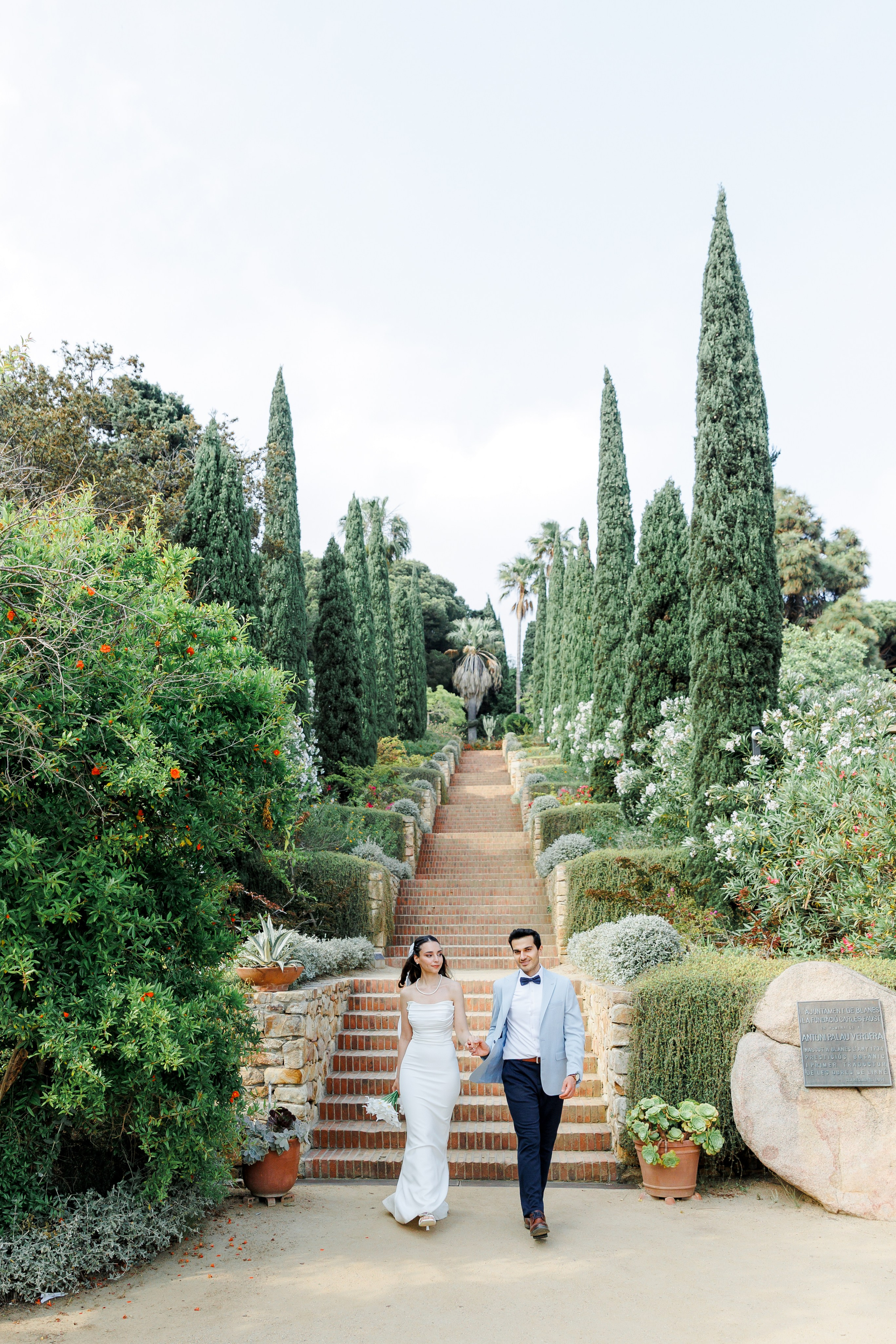 The bride and groom walking down the stone staircase in Marimurtra Botanical Garden