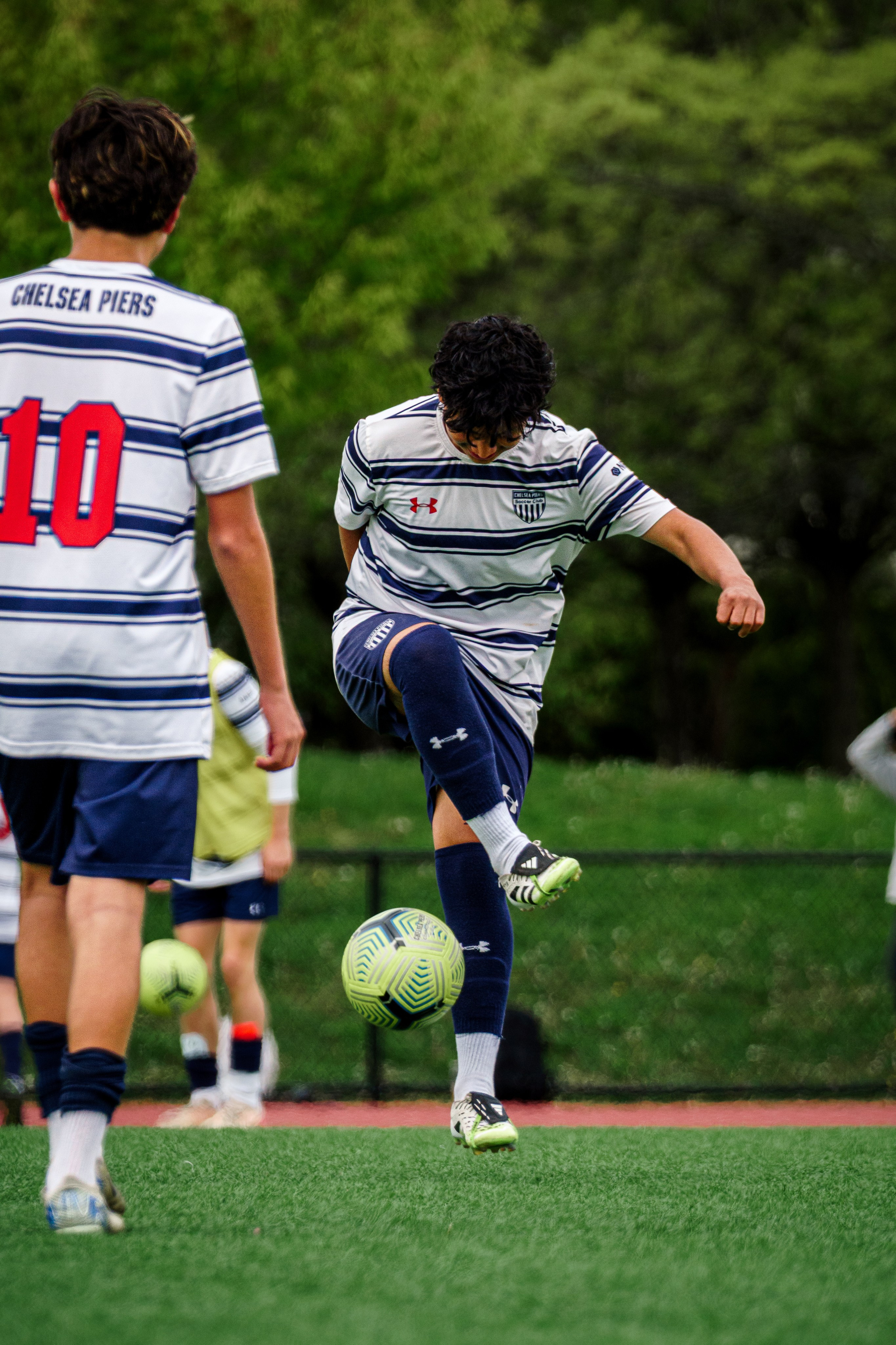 High school soccer player kneeling on the field boundary line with his head down, focused and still in a quiet moment before or after a play.
