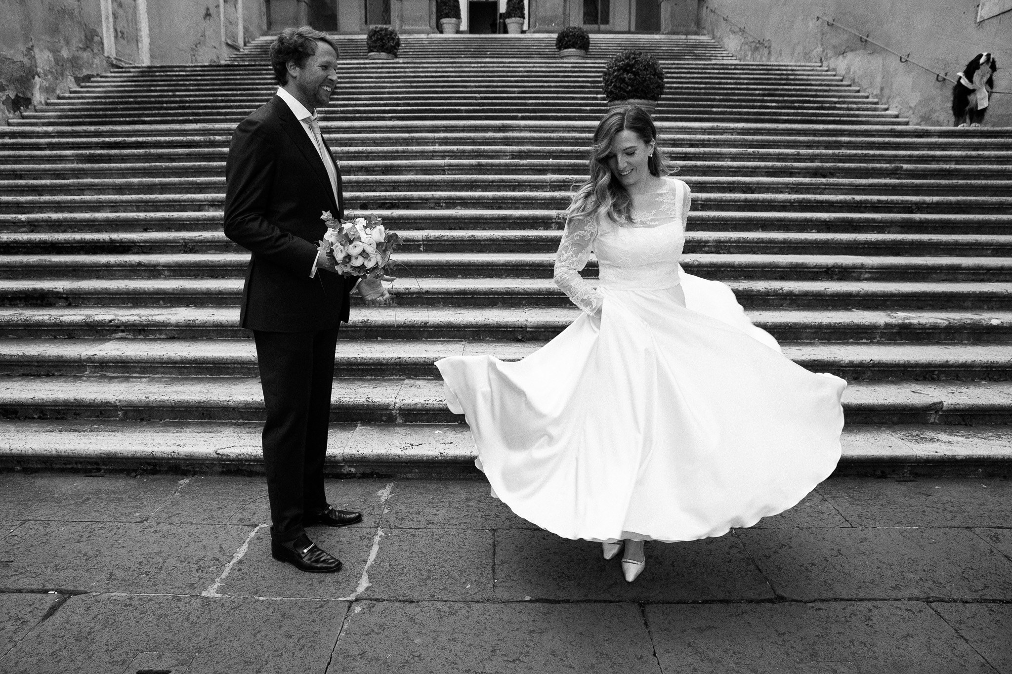 Newly weds are strolling hand in hand through a cobblestone street in Rome.