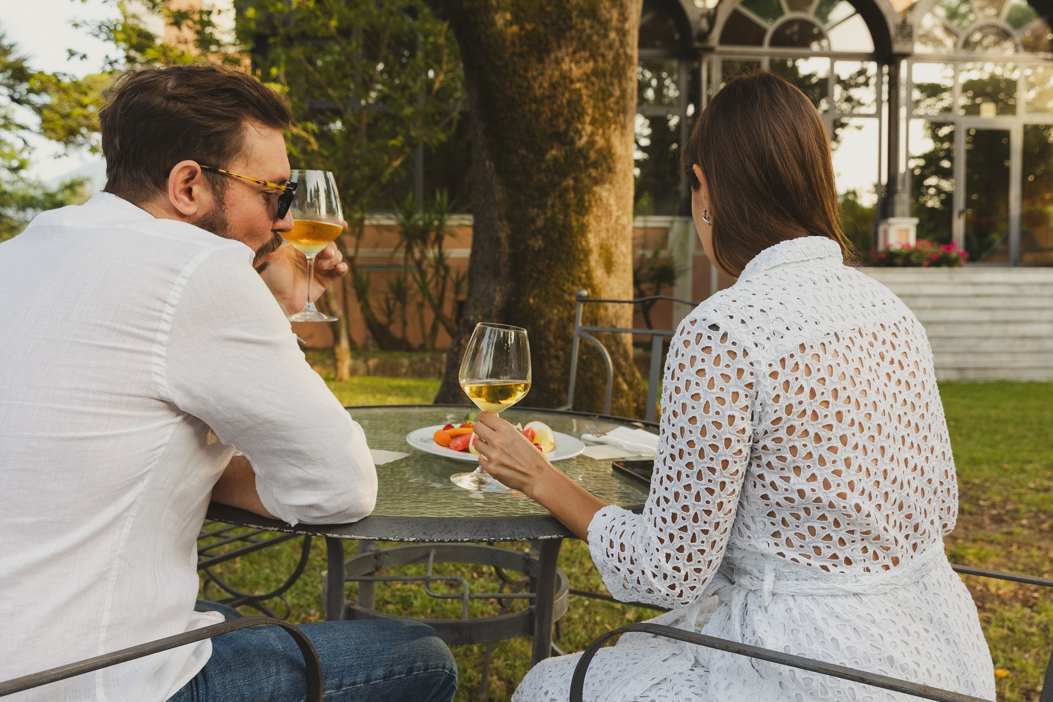 Couple enjoying a romantic drink in the lush garden of a luxury hotel in Rome.