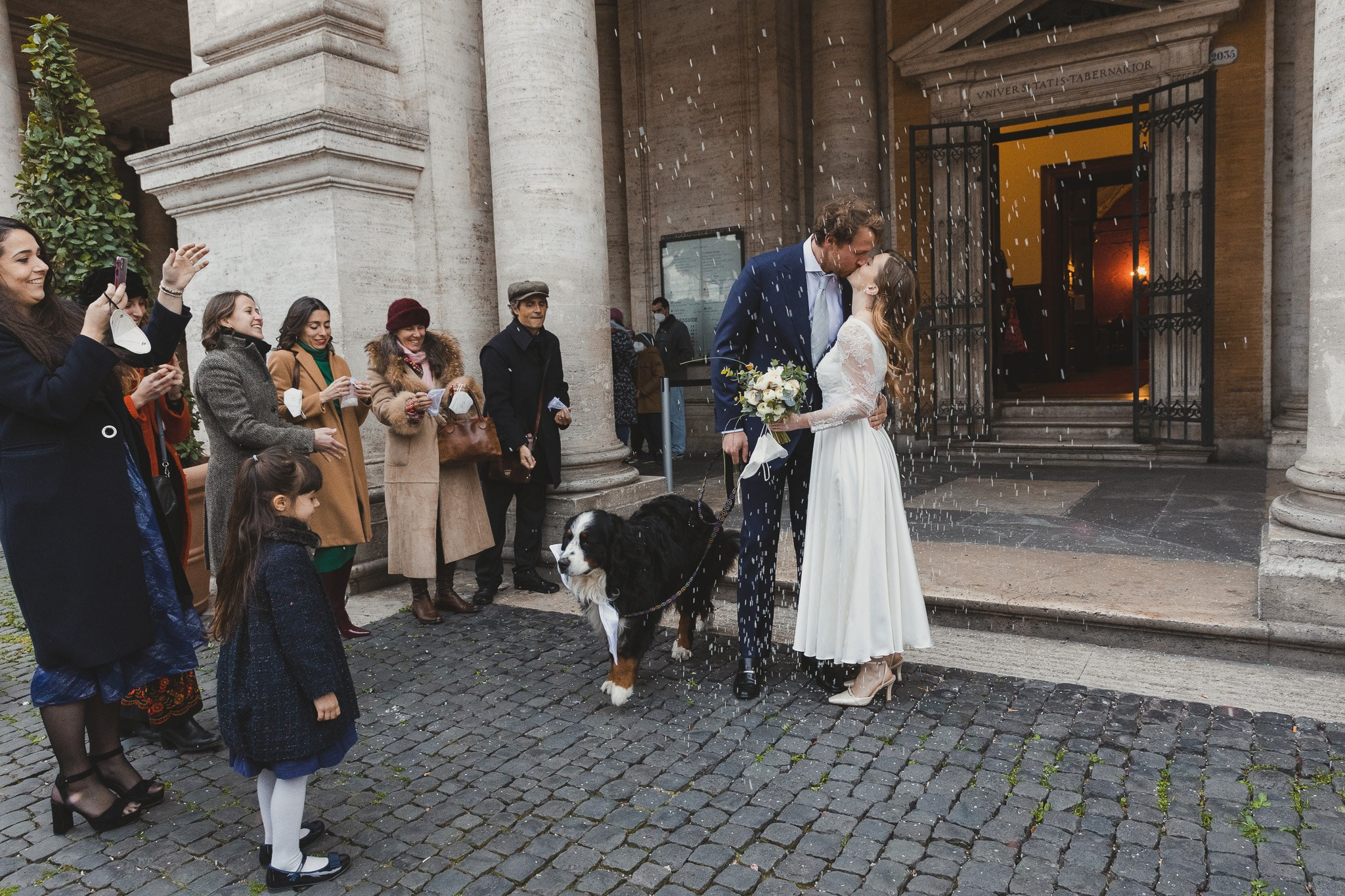 Wedding photograph in a picturesque setting at Campidoglio, Rome, a kiss after the official part of the wedding in the doorsteps, celebrating love of the amazing couple.