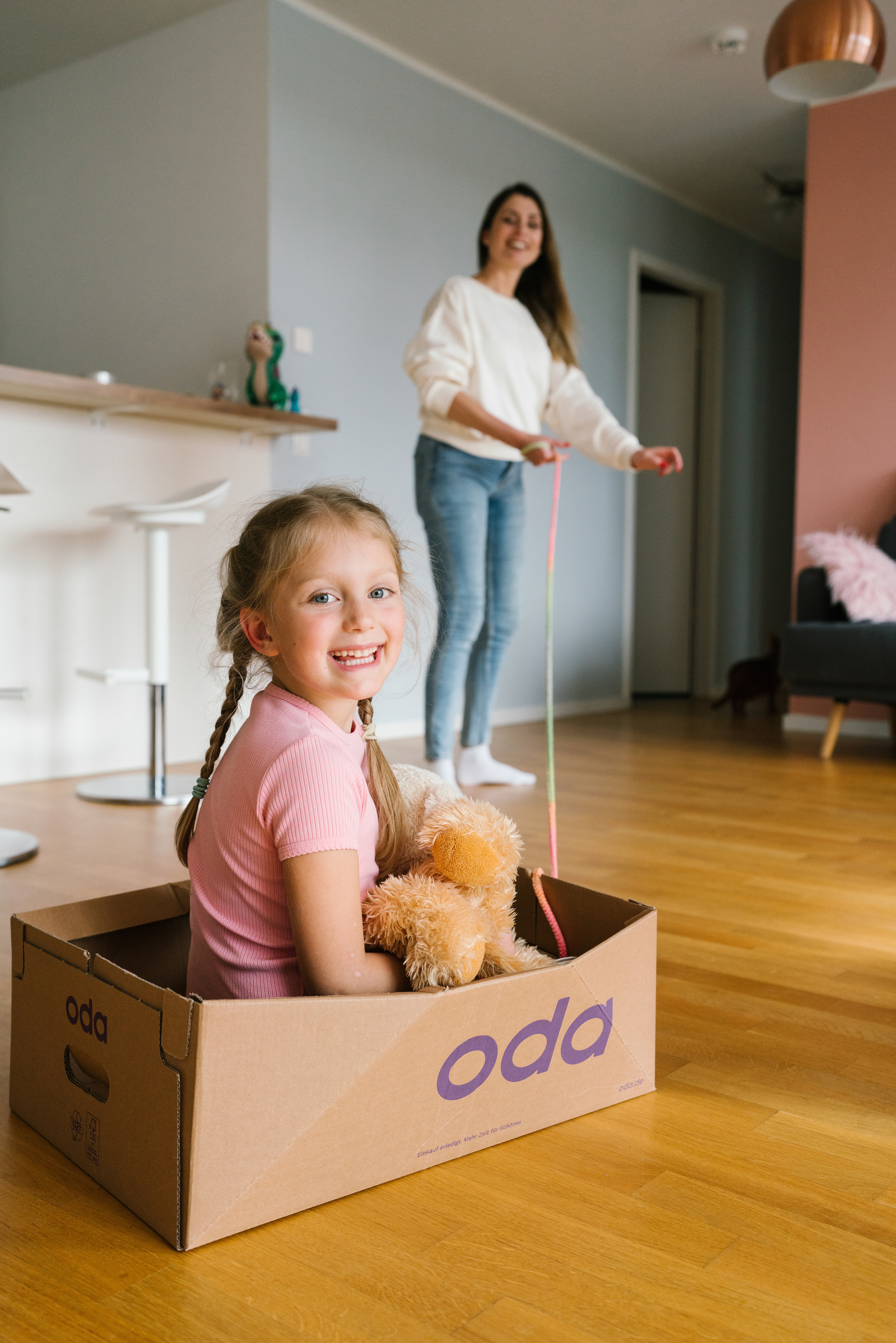 Child sitting in a box of Oda delivery and playing with mom