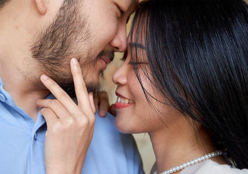 A black-haired, smiling woman lovingly embraces her partner's face in this close-up portrait from Prague's Vrtba Garden.