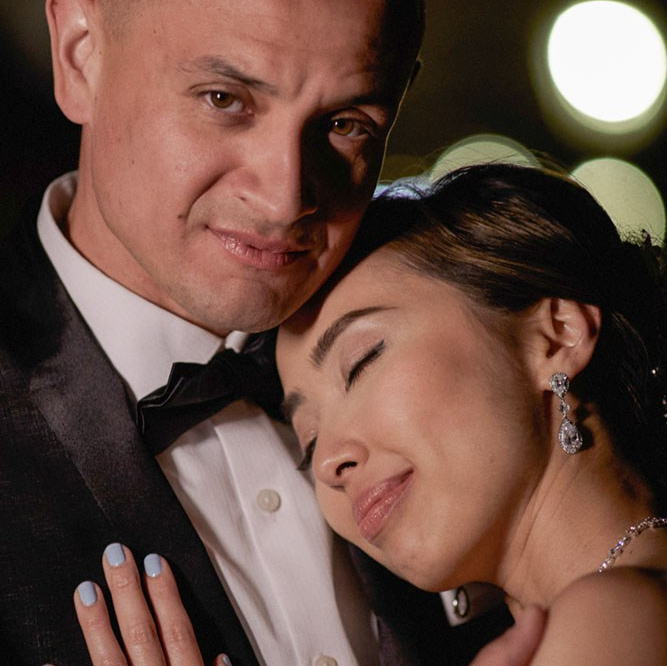 Smiling blonde-haired Swiss bride smiles lovingly towards her Italian groom as he looks towards the camera at a garden in Prague. 