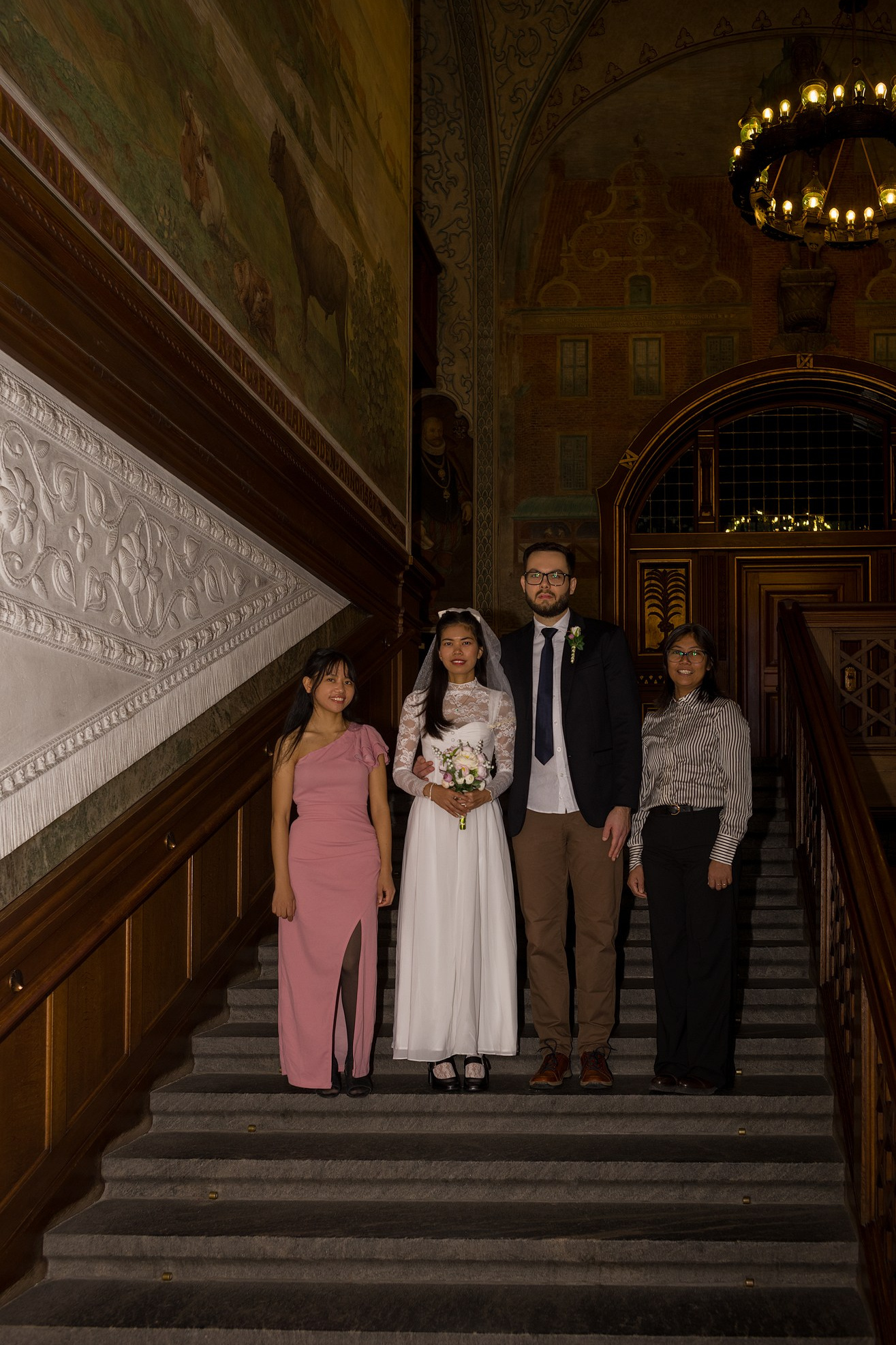 Bride and groom with family on the grand staircase in Copenhagen City Hall